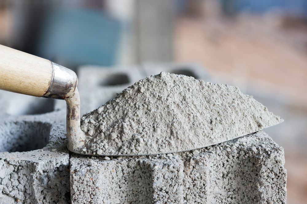 Trowel with A Mound of Gray Cement on A Concrete Block — DGW Wholesale Timber & Hardware in Maitland, NSW