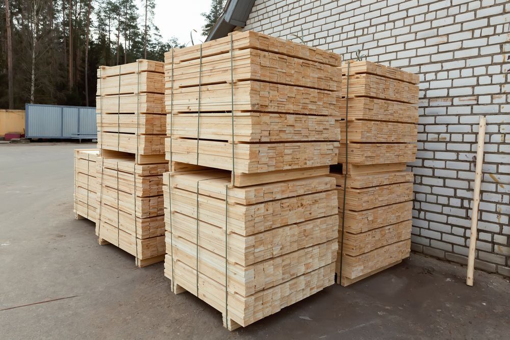 Stacks of Light-Colored Lumber on Pallets Outside a Building — DGW Wholesale Timber & Hardware In Maitland, NSW