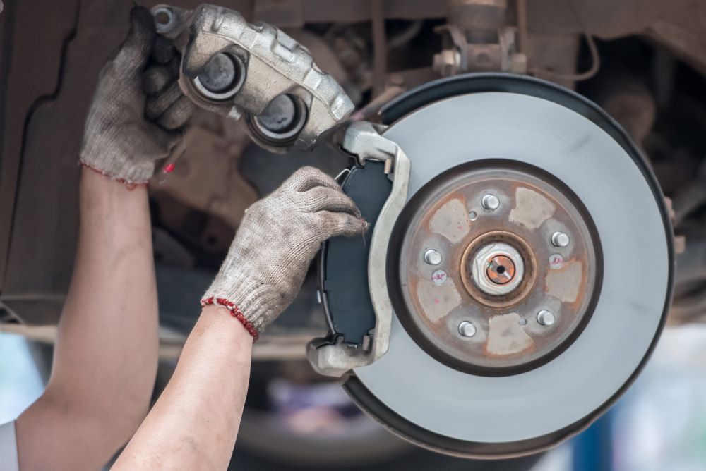 A Person is Fixing a Brake Pad on a Car — Skazas Automotive In Cardiff, NSW