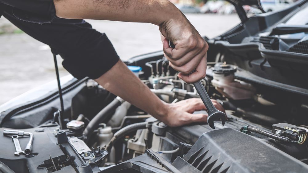 A Man is Working on the Engine of a Car With a Wrench — Skazas Automotive In Cardiff, NSW