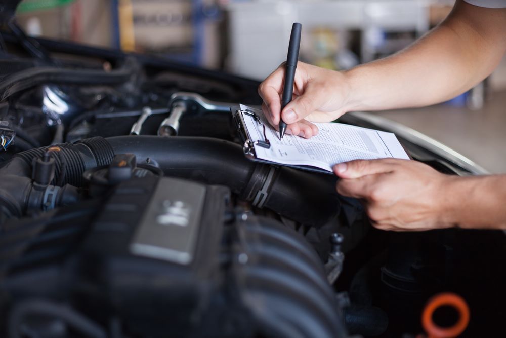 A Person is Writing on a Clipboard Under the Hood of a Car — Skazas Automotive In Cardiff, NSW