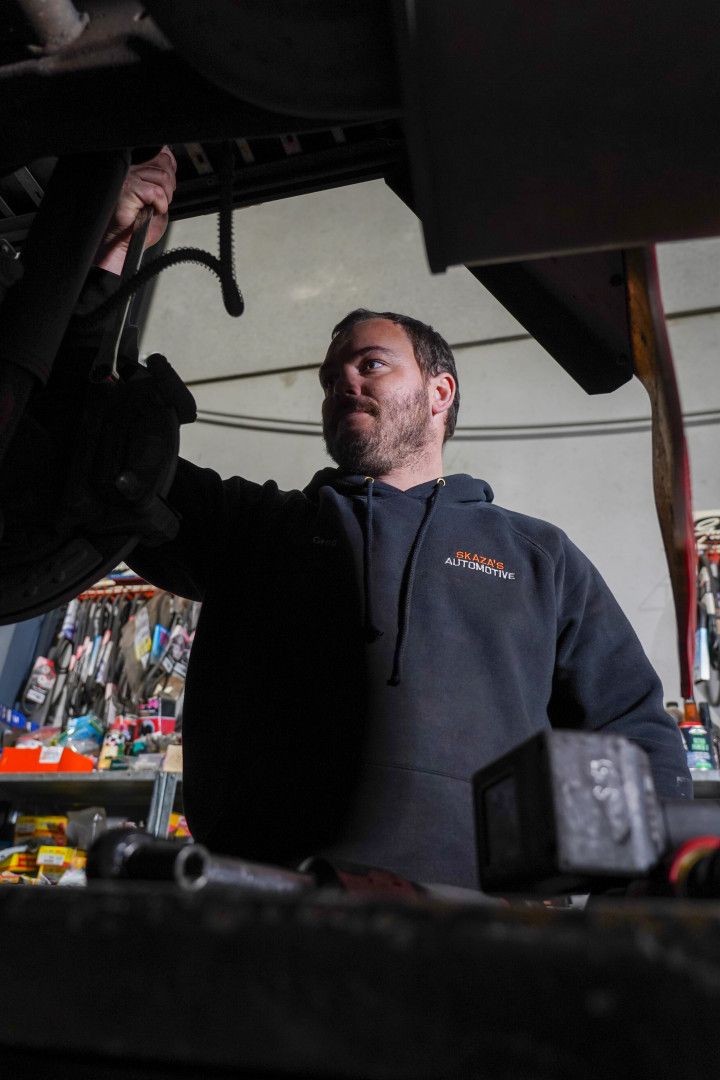 A Person is Fixing a Brake Disc on a Car in a Garage — Skazas Automotive In Cardiff, NSW