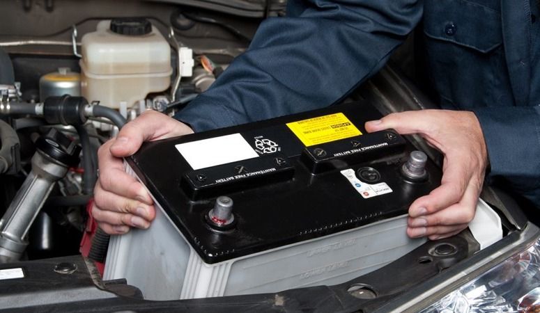 A Person is Holding a Car Battery in Their Hands — Skazas Automotive In Cardiff, NSW