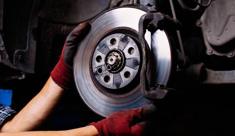 A Person is Fixing a Brake Disc on a Car — Skazas Automotive In Cardiff, NSW