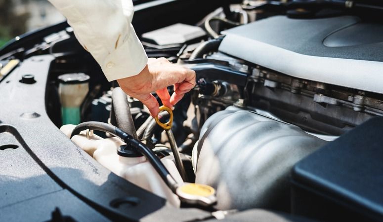 A Person is Checking the Oil in a Car With a Dipstick — Skazas Automotive In Cardiff, NSW