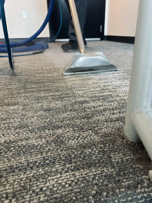 Vacuum cleaner head on patterned carpet in an office room