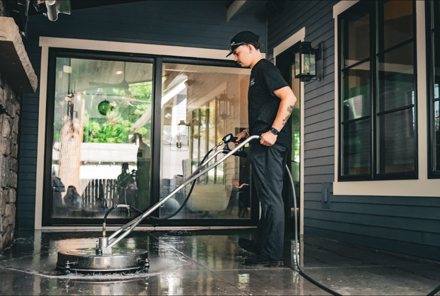 Person pressure washing a wet porch outside a house