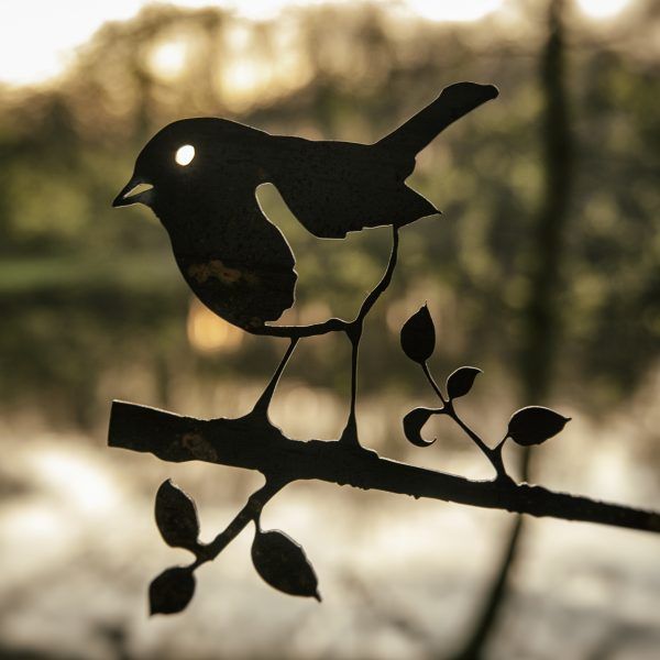 Een silhouet van een vogel die op een tak met bladeren zit