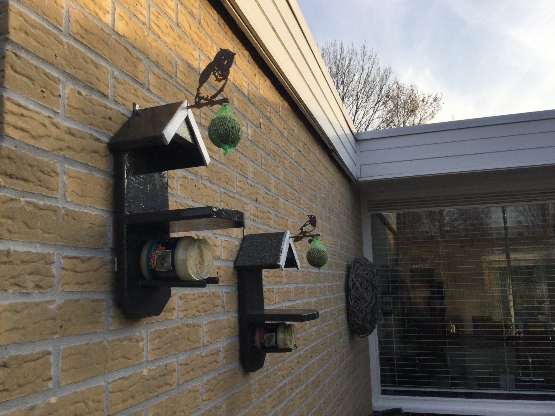 Een bakstenen muur met daaraan een voederbak voor vogels