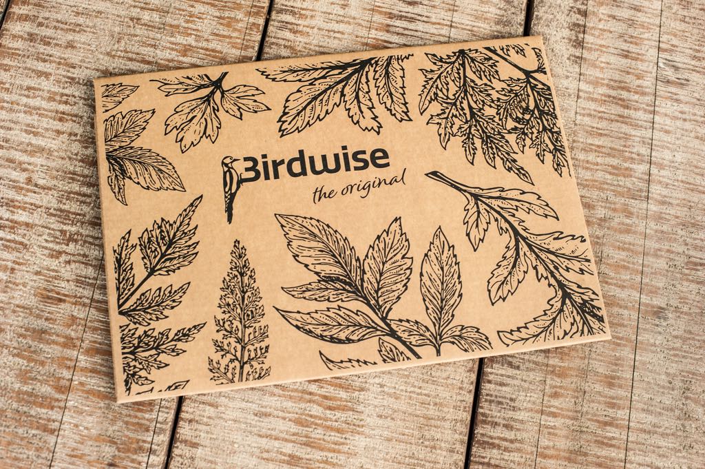 Een kaartje met de tekst birdwise ligt op een houten tafel.
