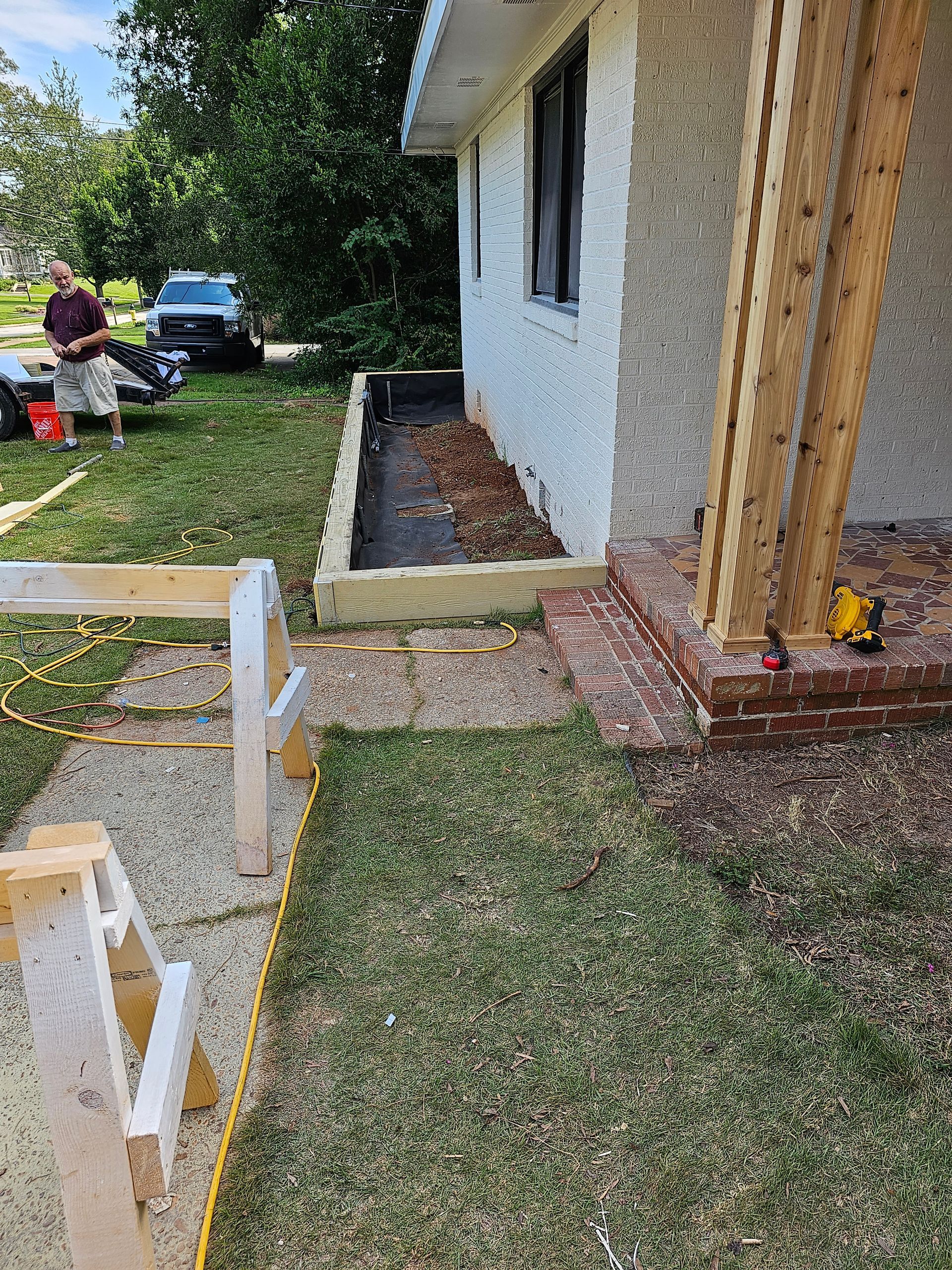A house under construction; a walkway, and a person in the background.
