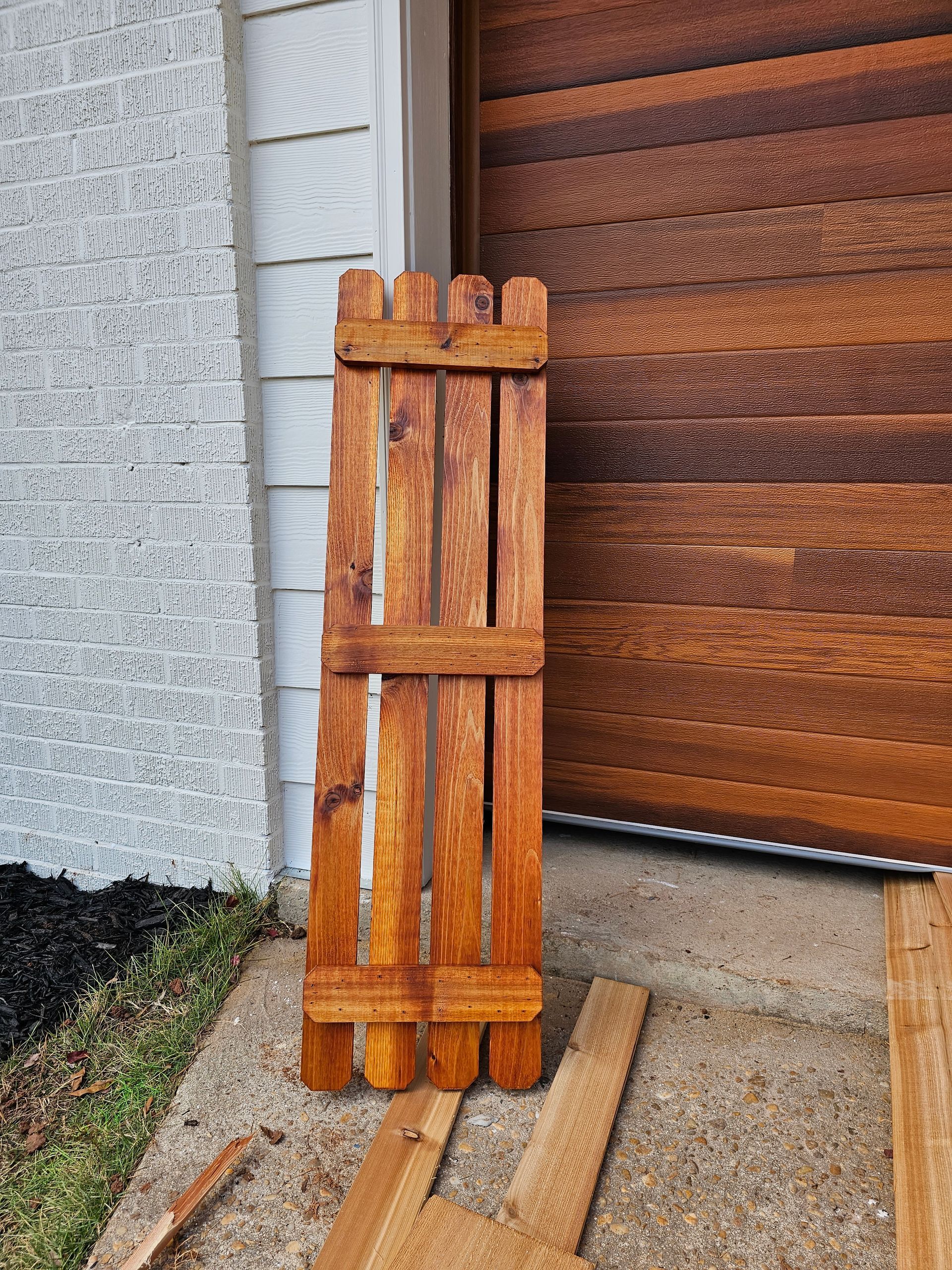 Brown wooden shutter propped against a door.
