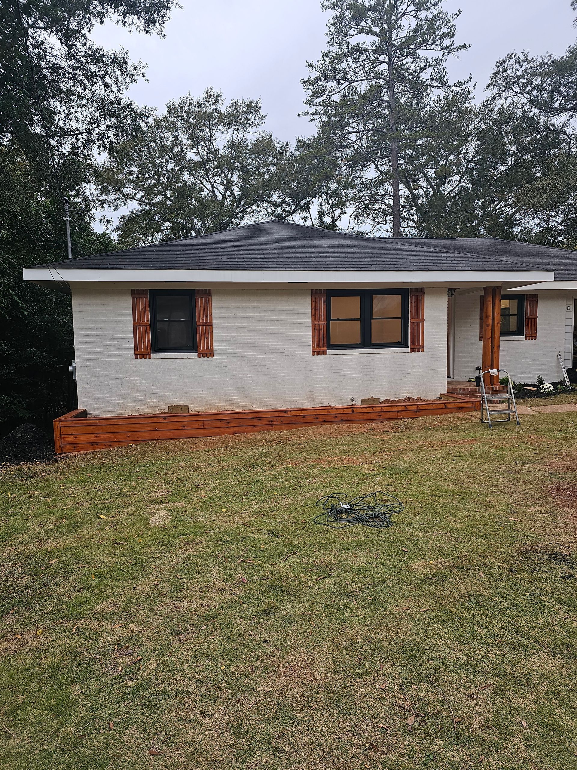 White brick bungalow with brown shutters and trim; front yard with dead grass.