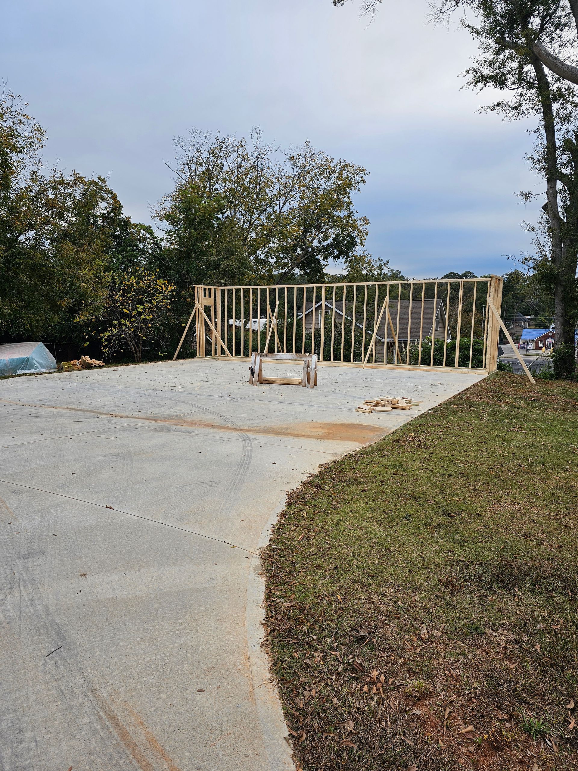 Concrete driveway with wooden frame for a structure; cloudy sky and trees in the background.