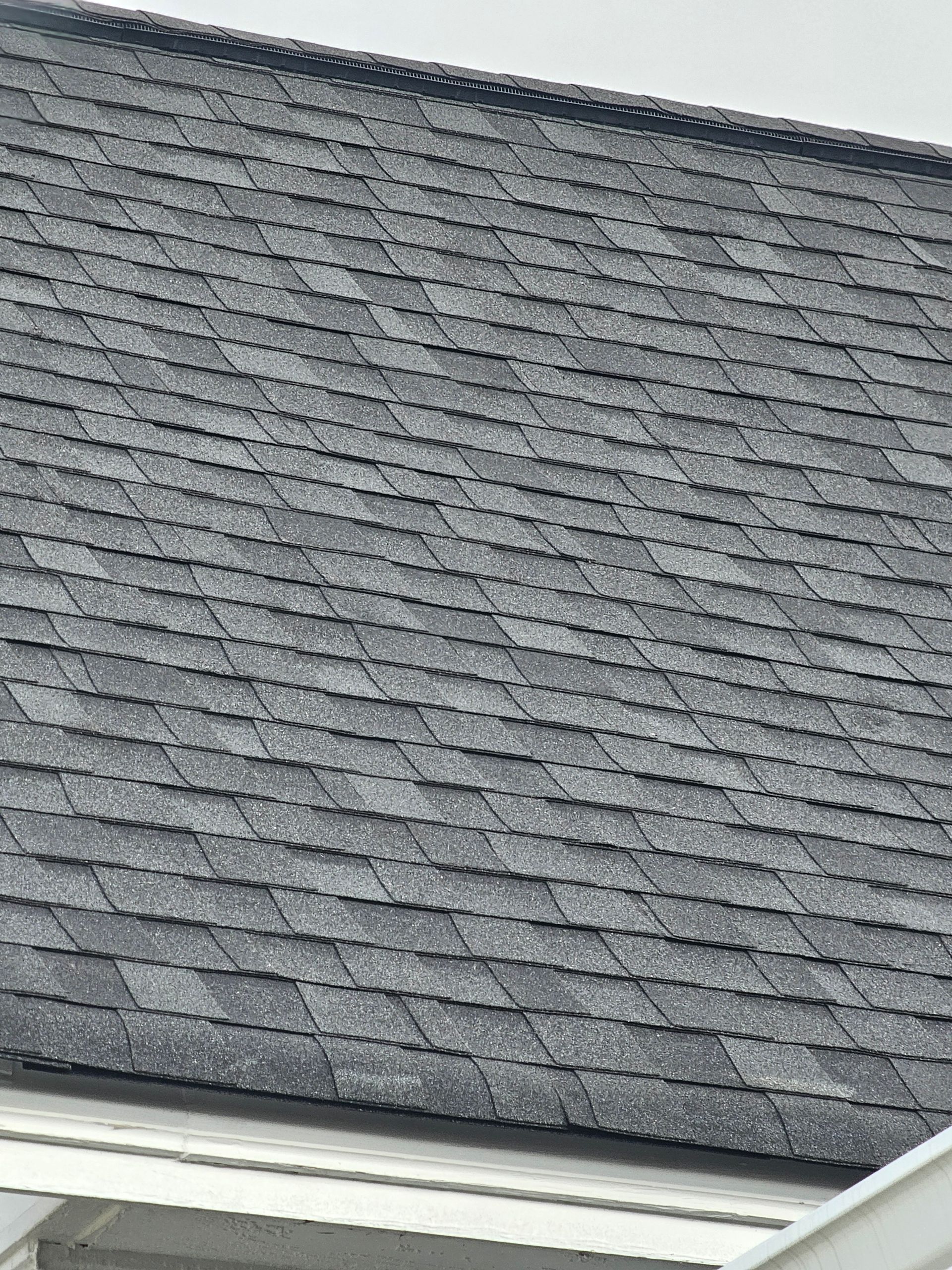 Gray asphalt shingle roof on a building, showing texture and pattern.