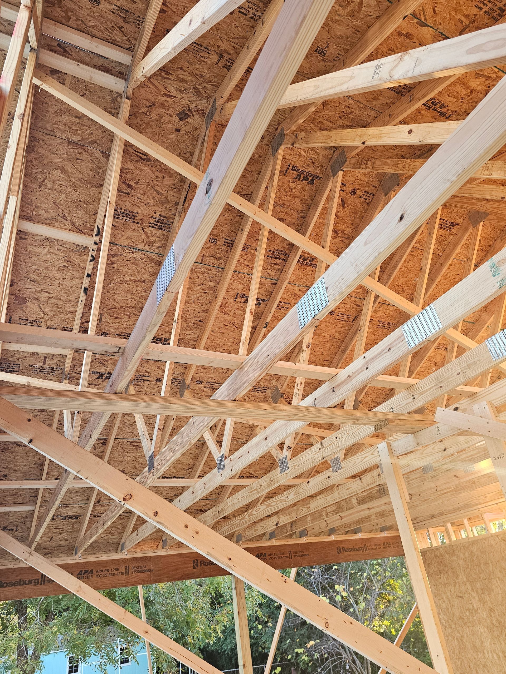 Wooden roof trusses and sheathing under construction, outdoors.
