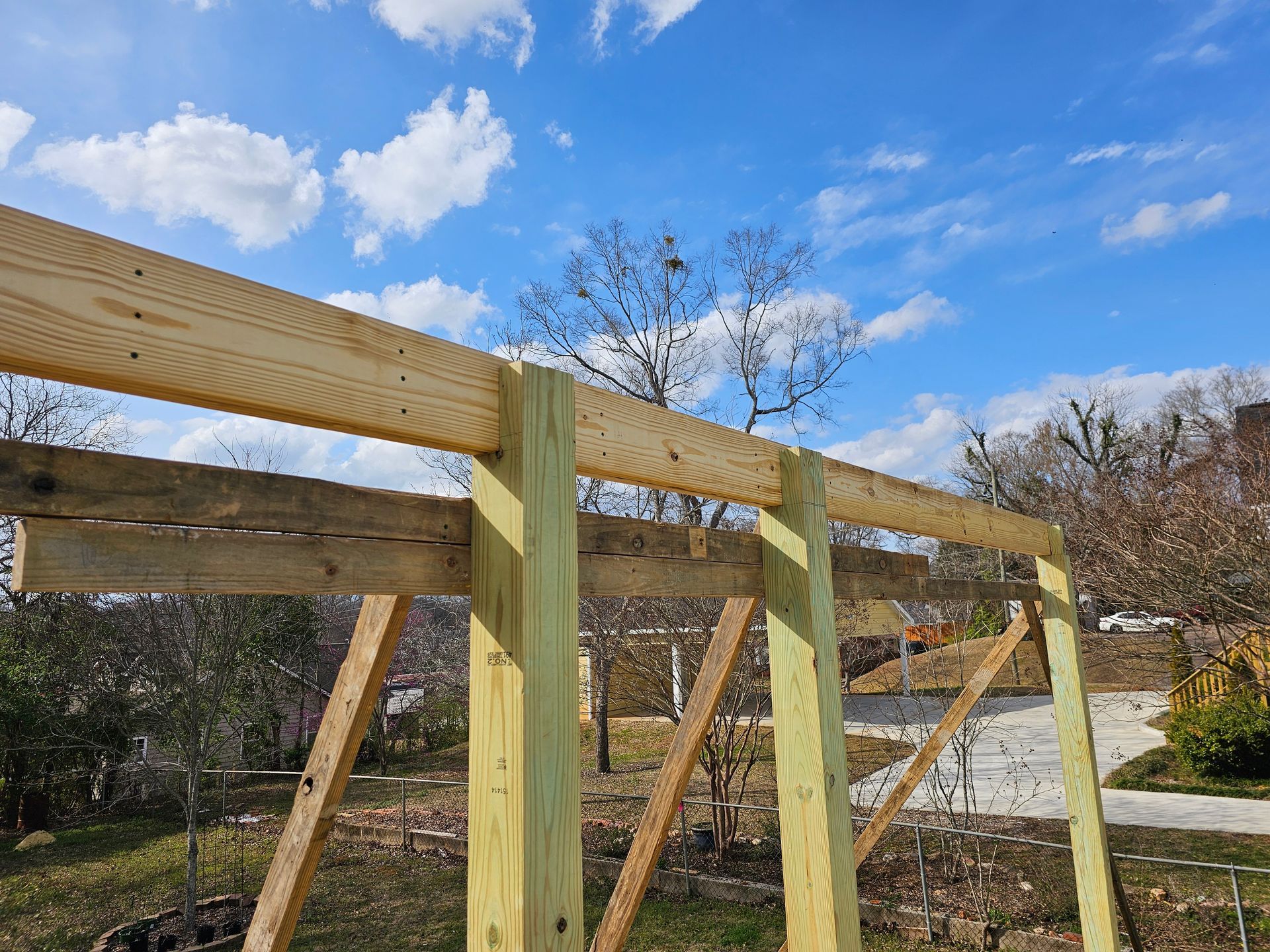 Wooden frame structure under construction against a partly cloudy sky.