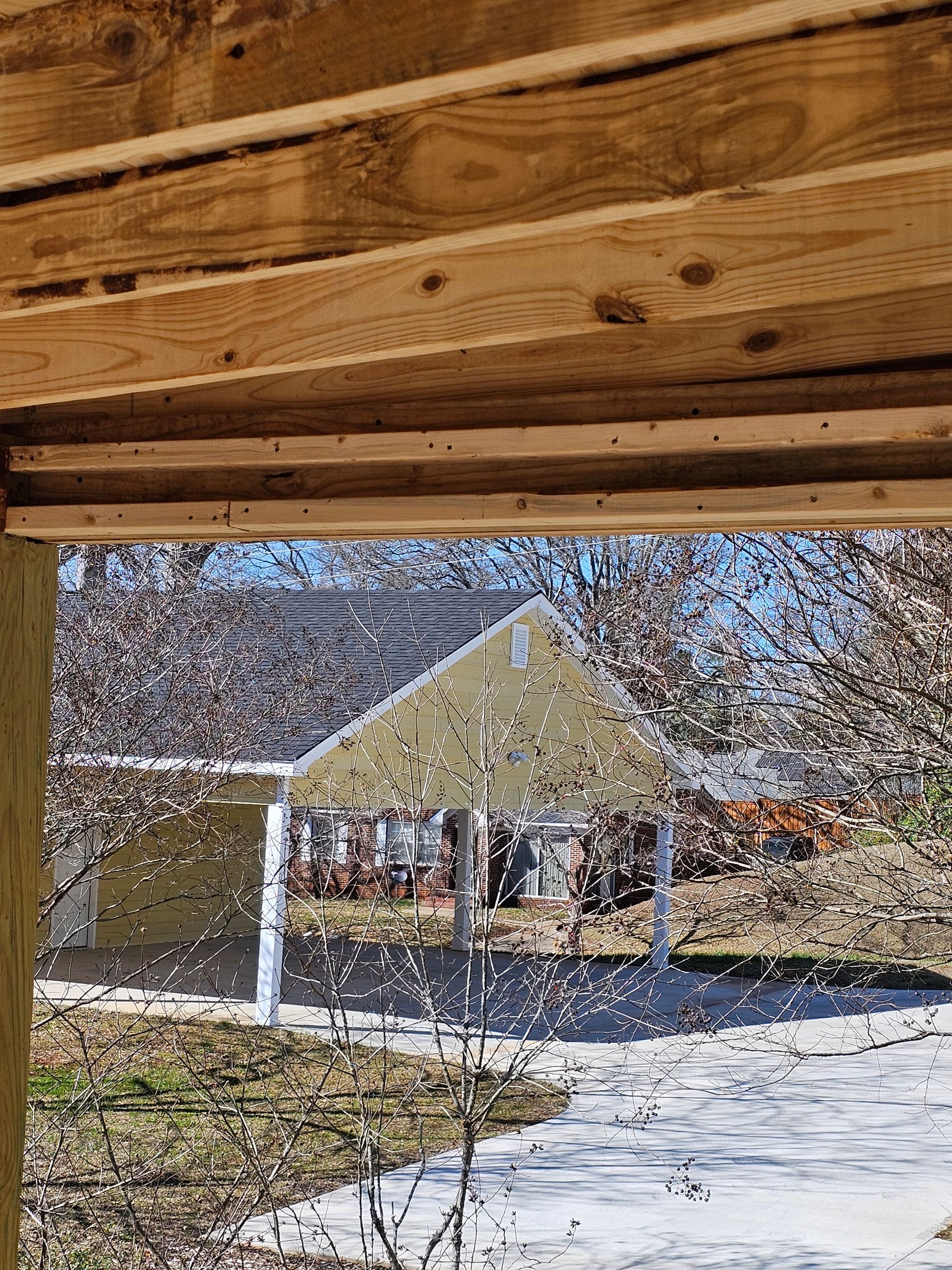 View from a wooden structure. A structure with a peaked roof is visible in the distance.