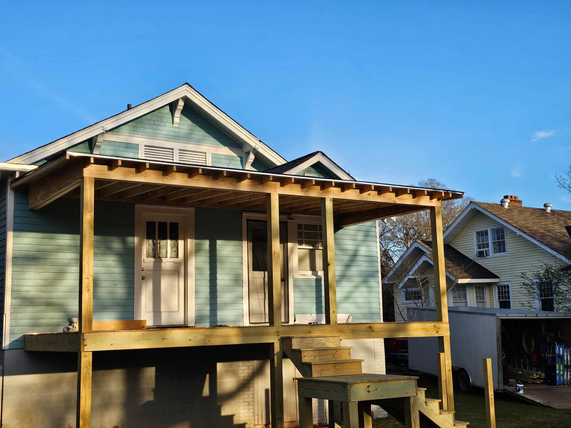 Wooden porch under construction on a blue house. Sunny day.