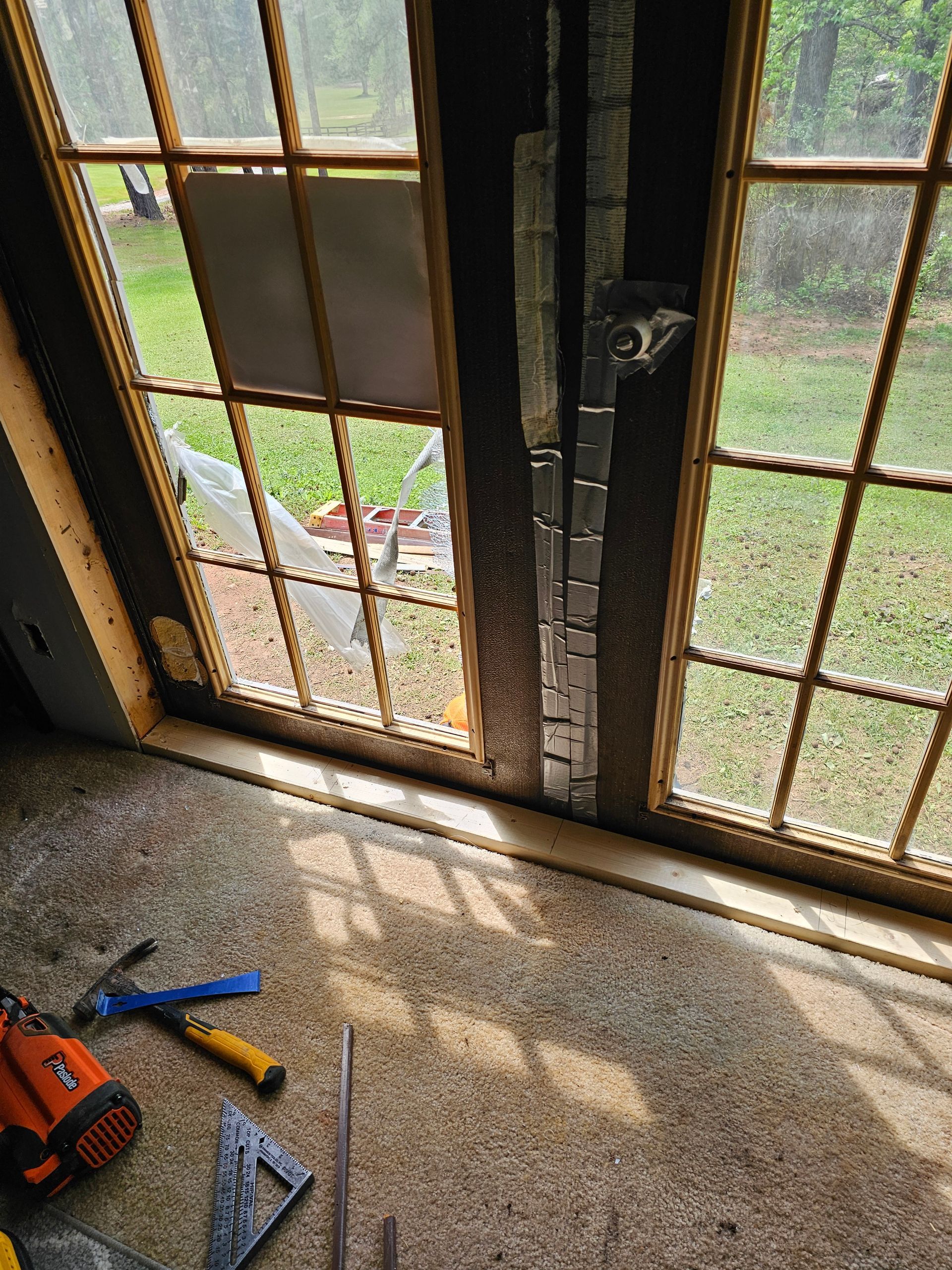 Damaged window with tools on the floor. Torn glass and exposed framing.