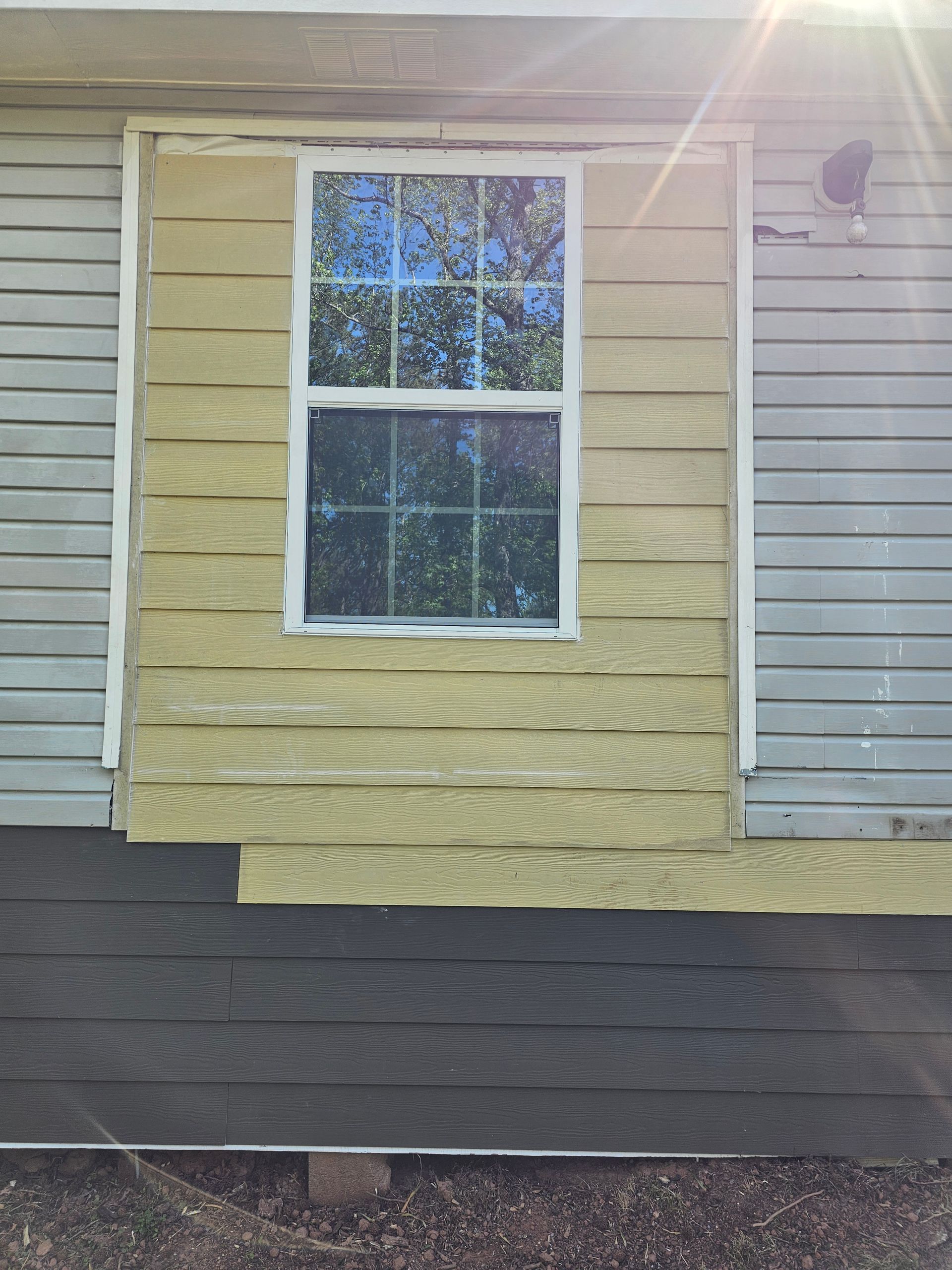 House exterior with window; replacement siding in progress.