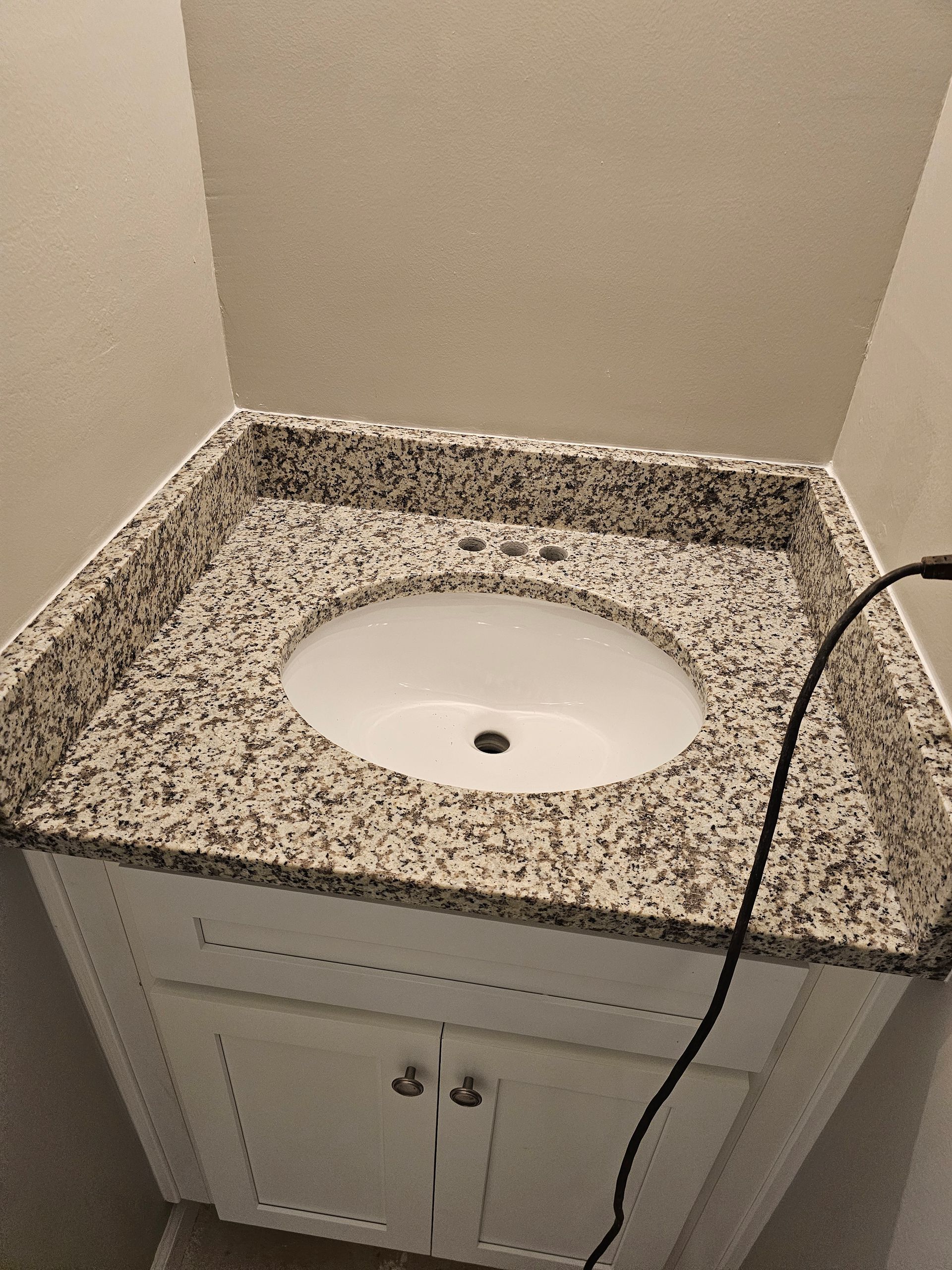 White vanity with granite countertop and oval sink.