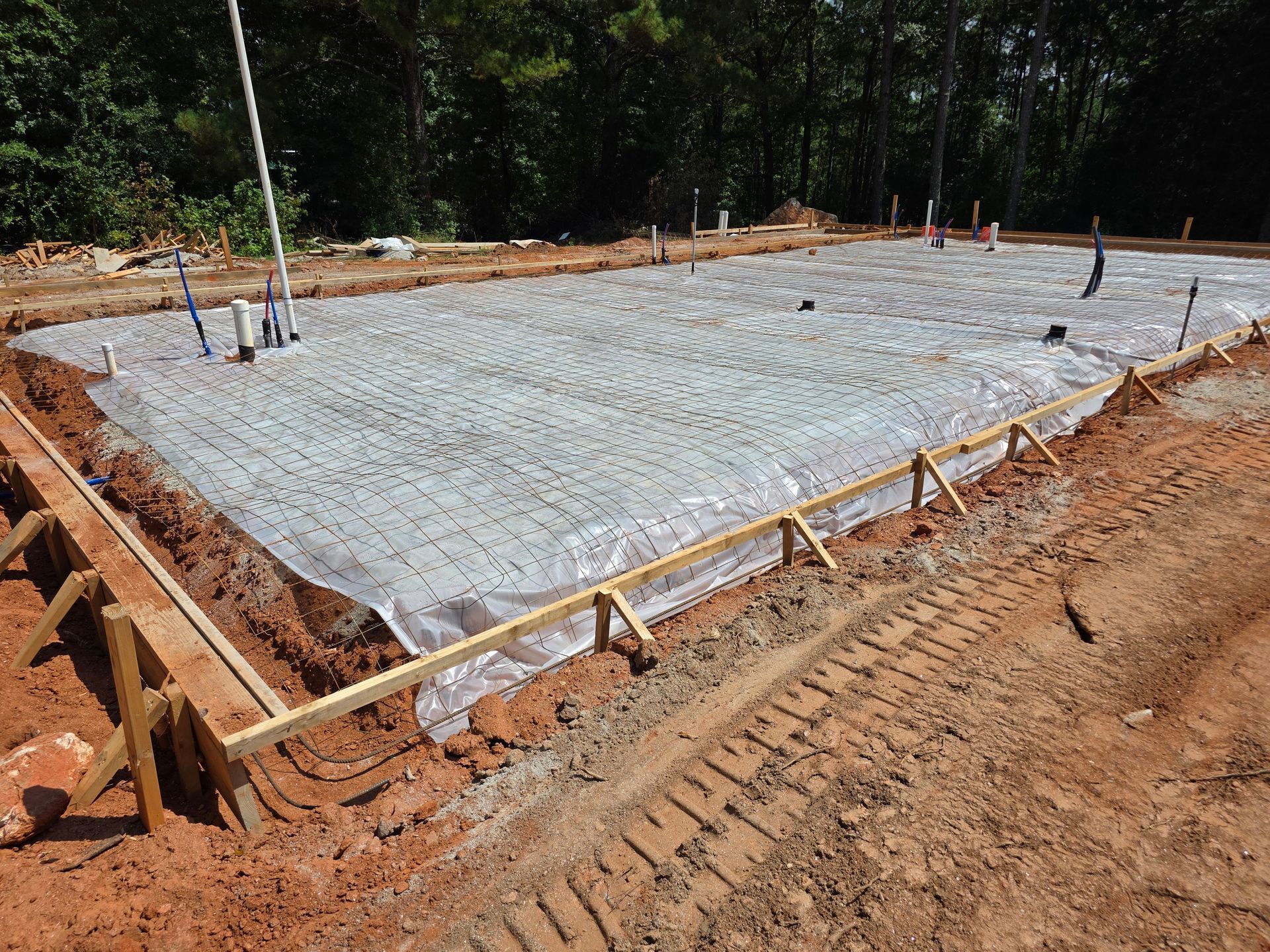 Prepared construction site with wooden frame and plastic covering, ready for concrete pouring.