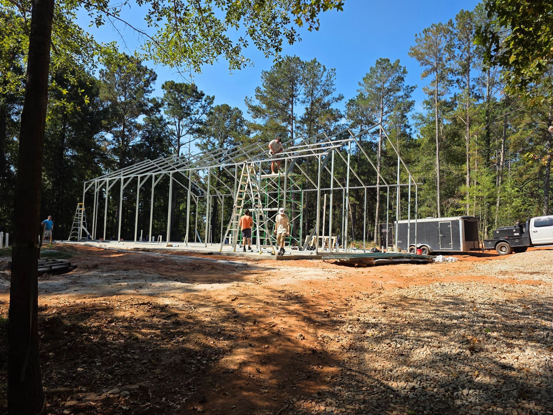 Construction of a wooden framed building in a wooded area; workers on the frame.