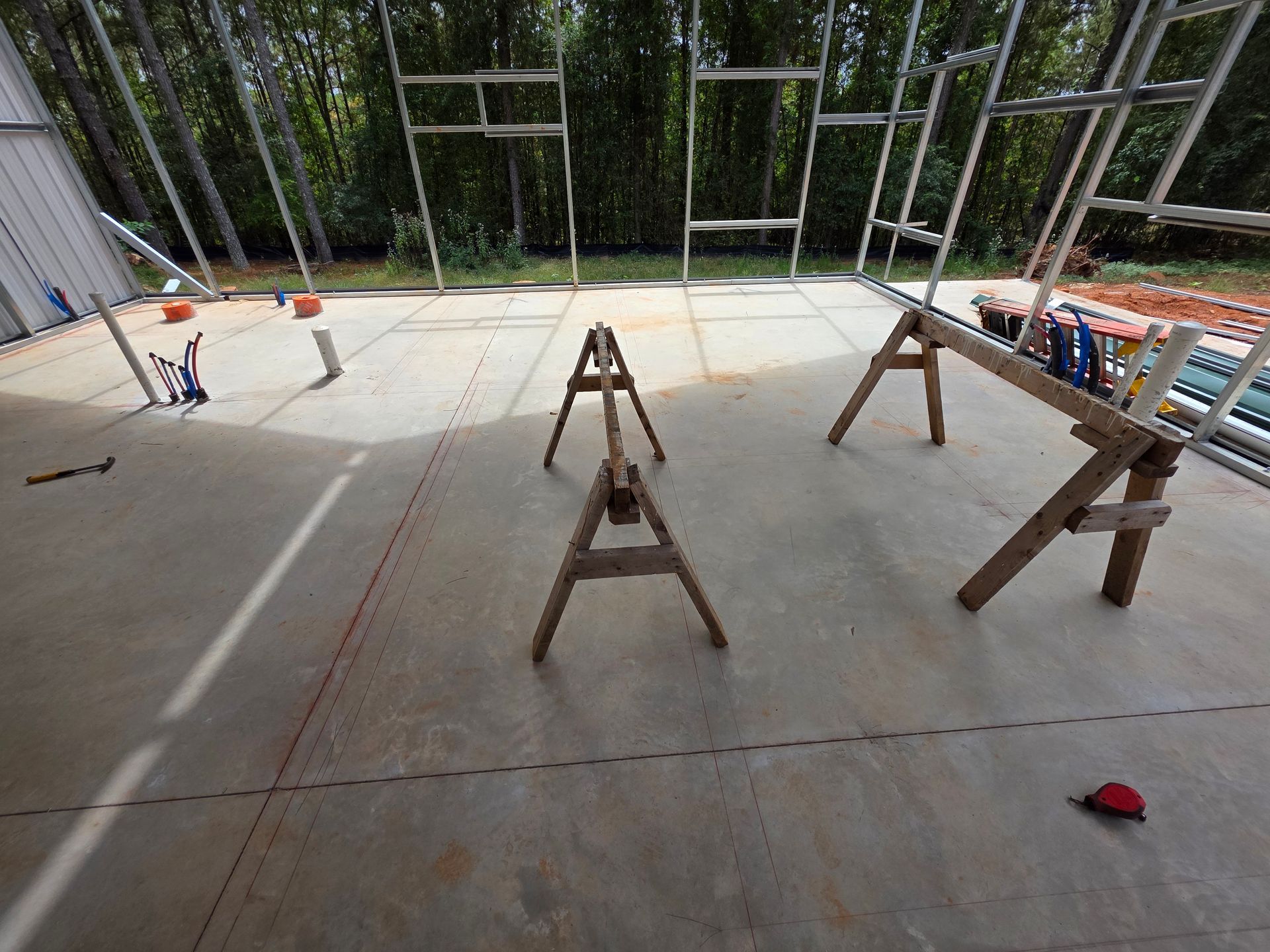 Interior view of a concrete floor with scaffolding, sawhorses, and tools; construction site.