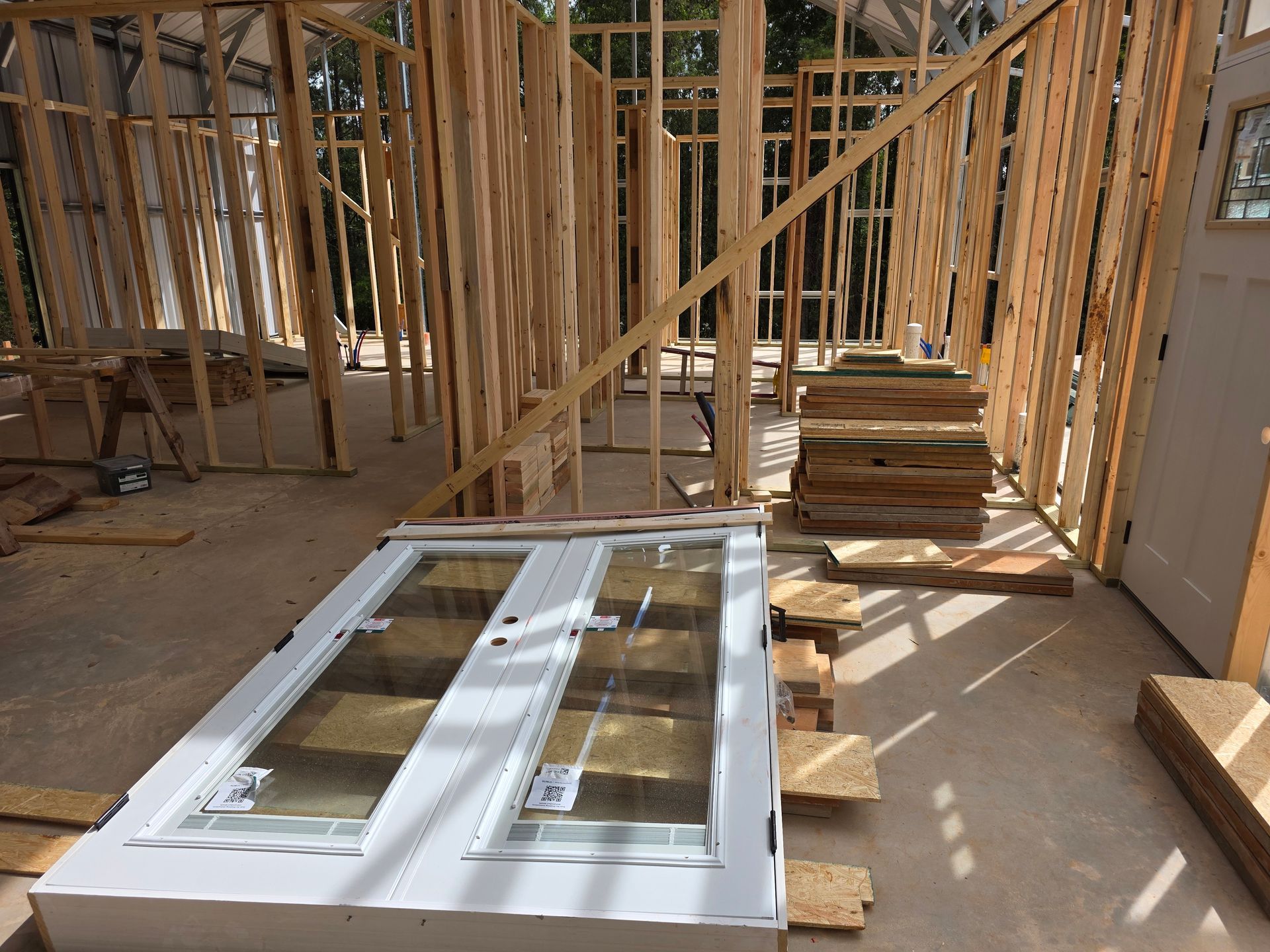 Interior view of a building under construction, with wooden framework and a double-door laying on the floor.