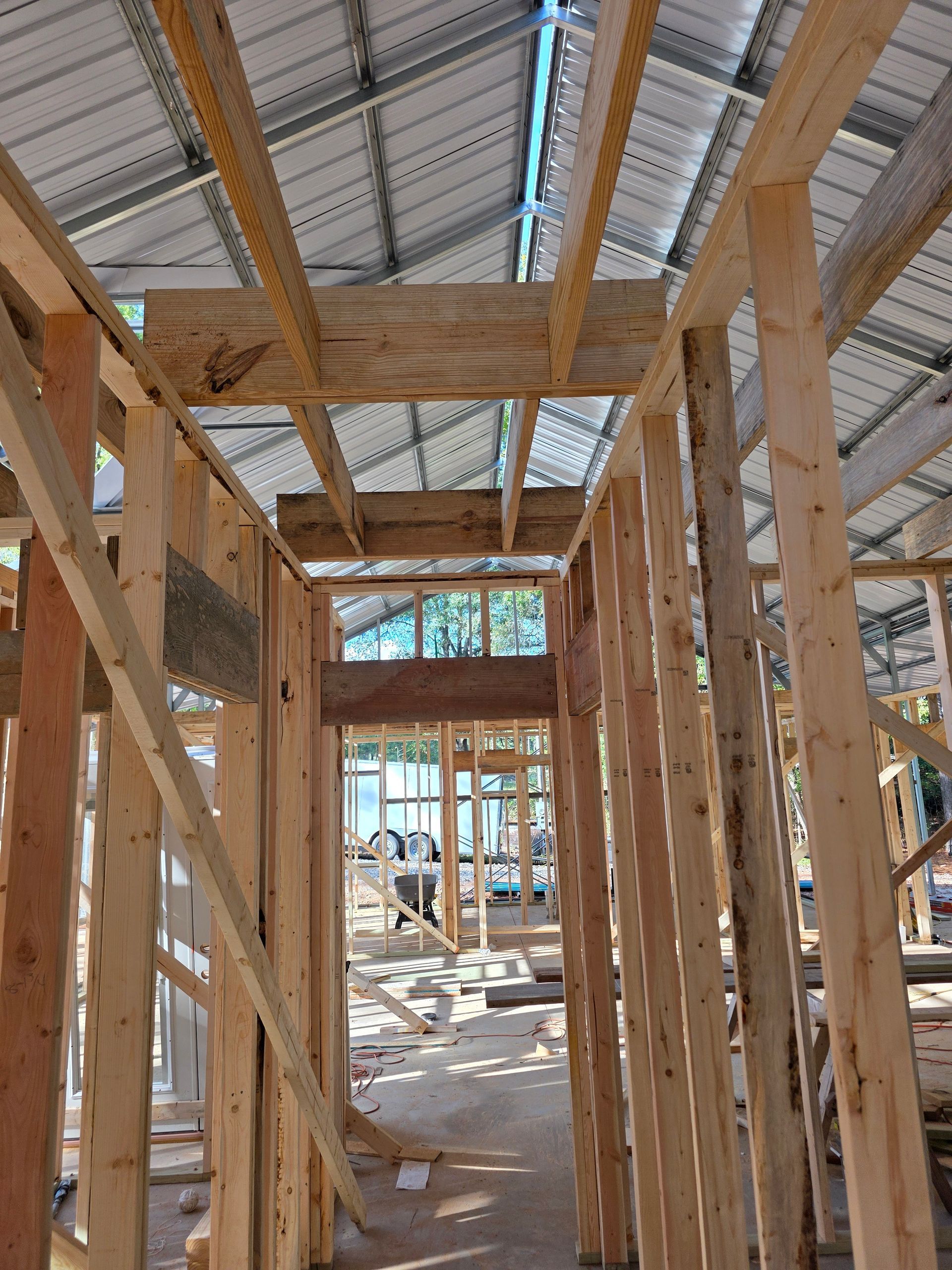 Wooden framework of a building under construction, with visible roof and doorway.