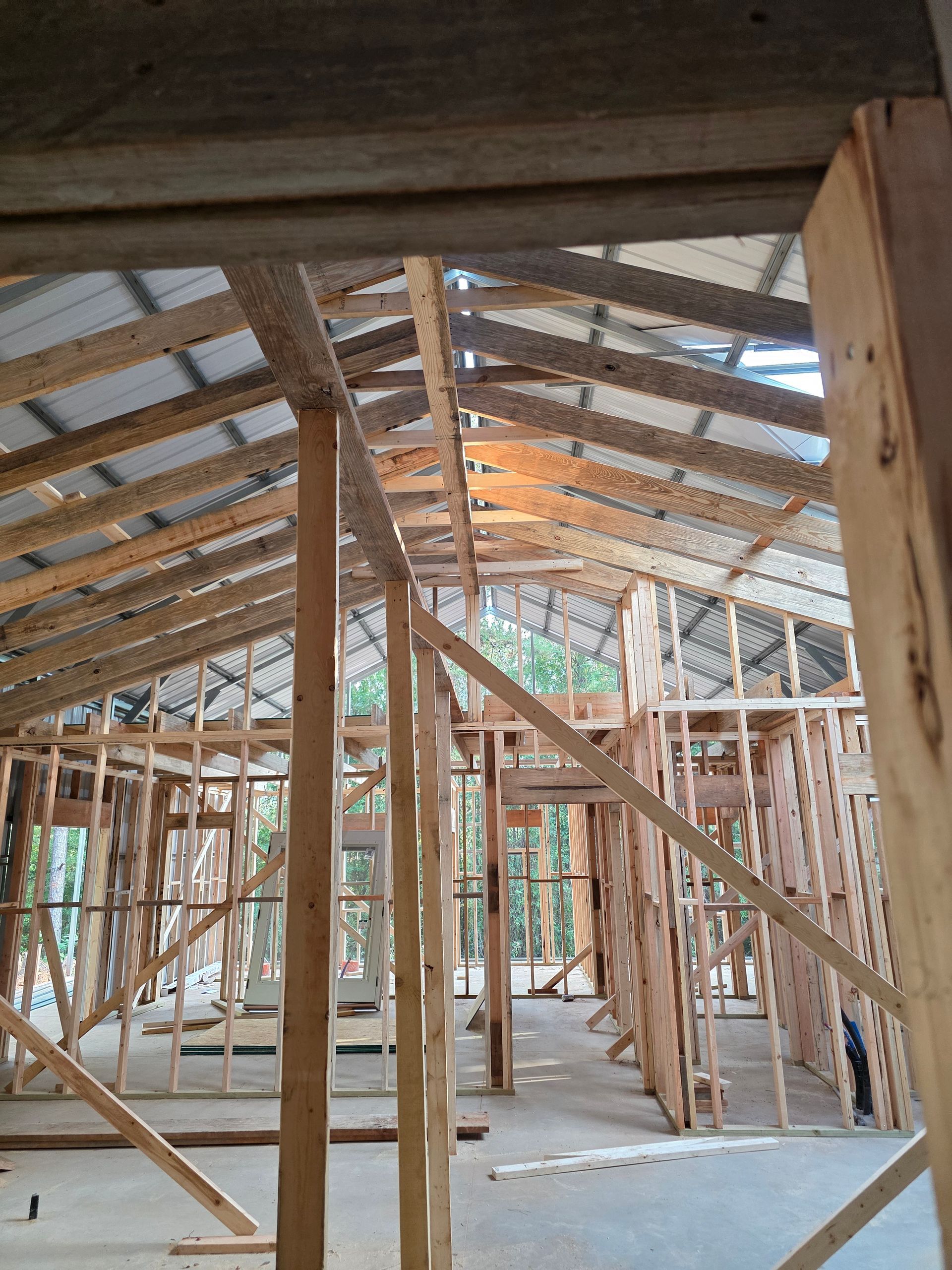 Interior of a building under construction, wooden frame with metal roof visible.