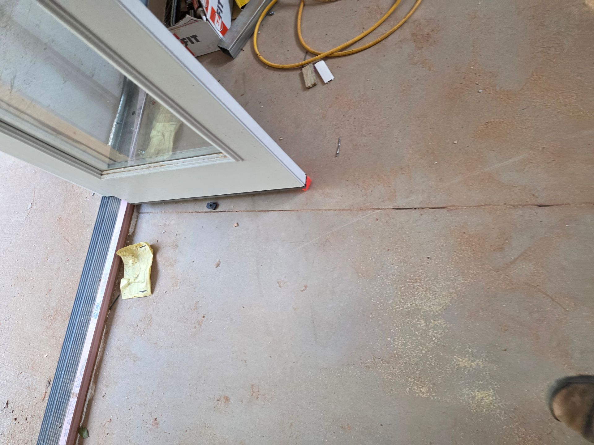 Door frame on a concrete floor with tools and a power cord.