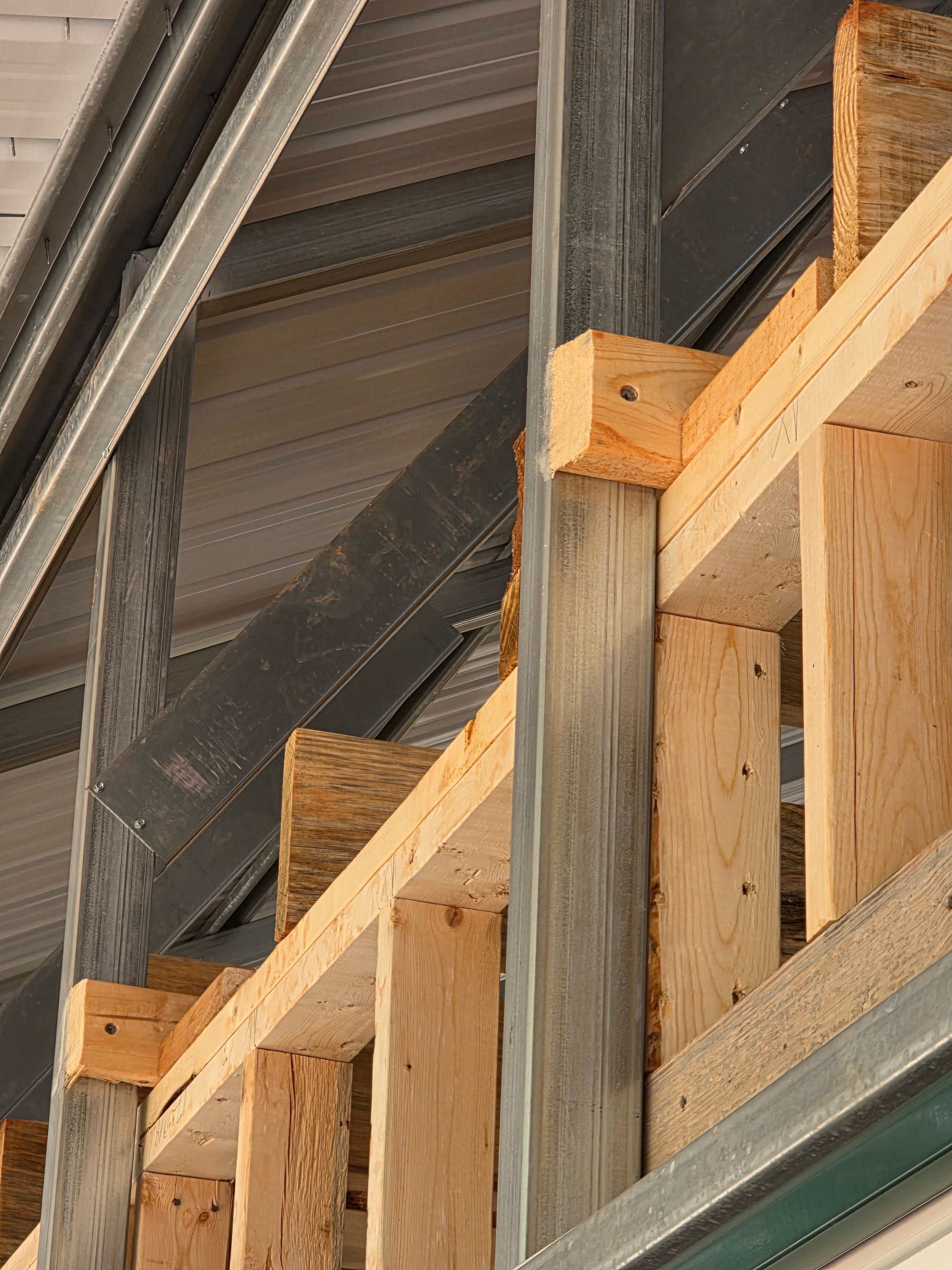 Wooden and metal framing of a building under construction; beams and OSB boards are visible.