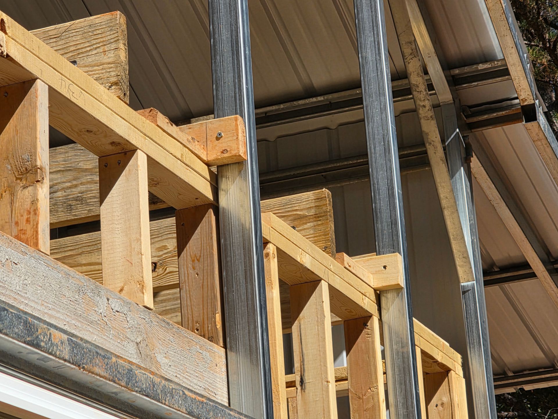 Wooden frame of a building under construction, with metal support beams and partially installed roofing.