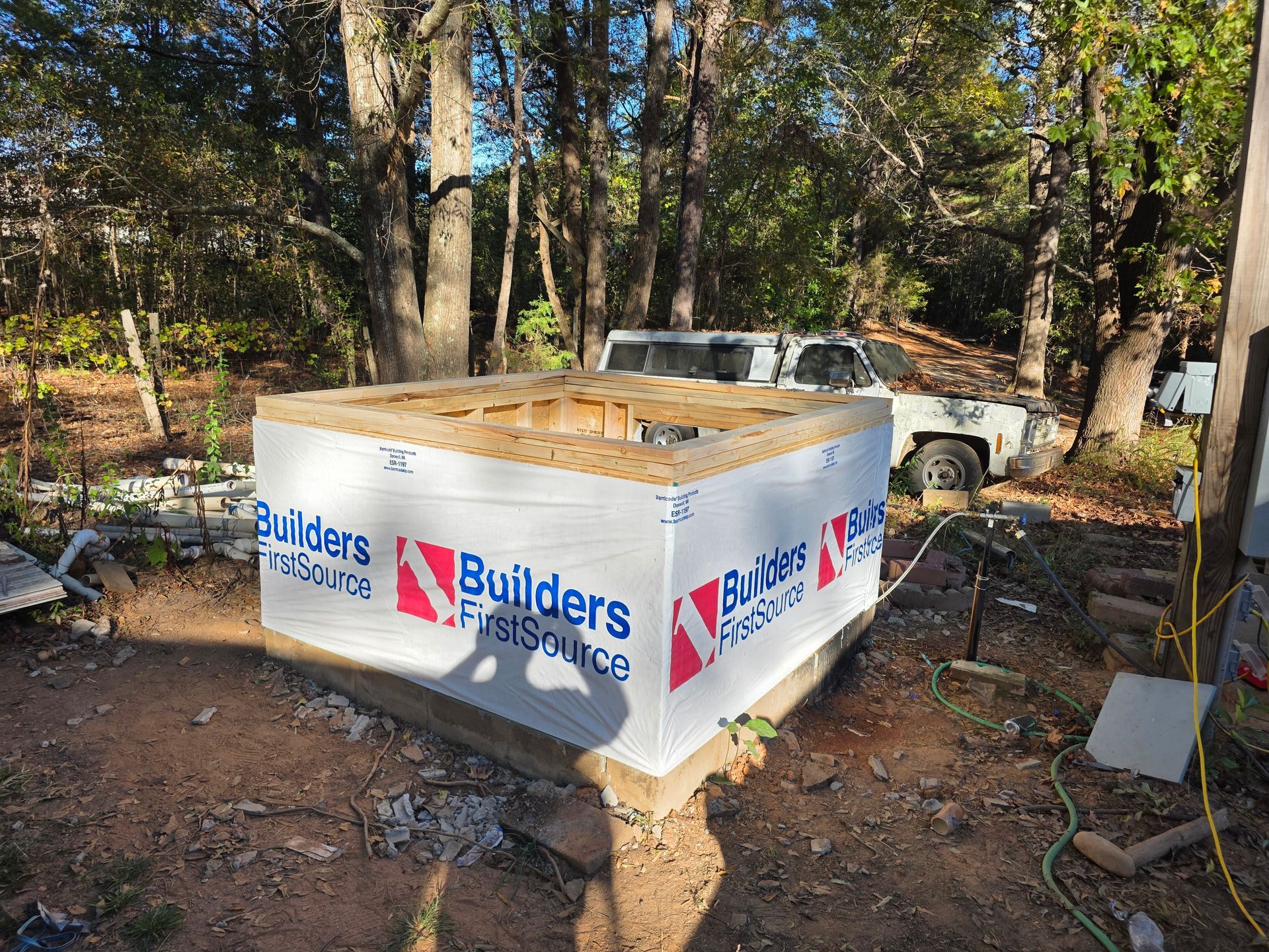 A wood-framed structure wrapped in white sheathing, branded with 