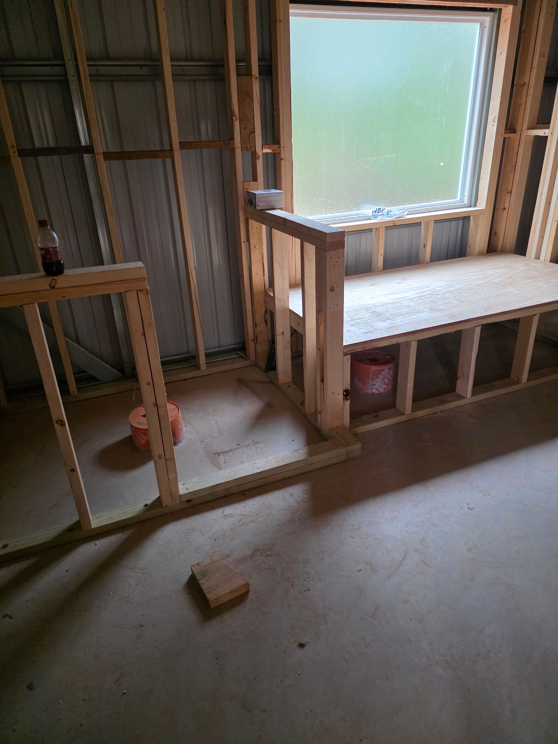 Interior view of a room under construction with a window and a wooden platform.