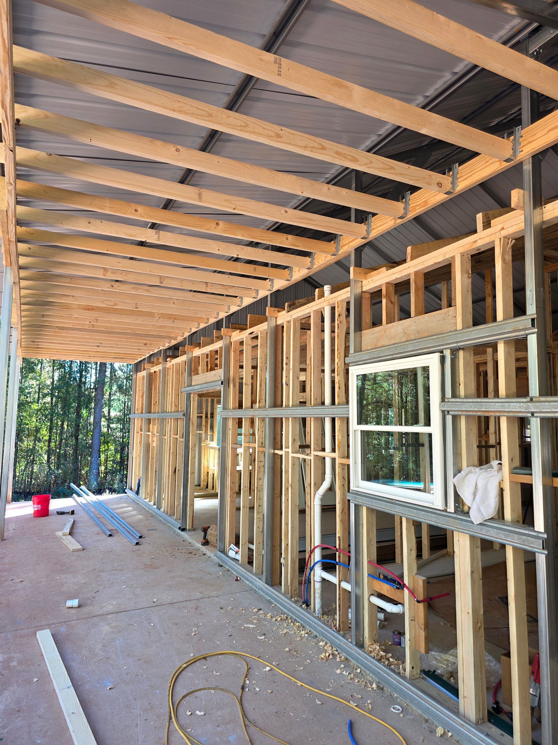 Wooden framework of a building under construction, with exposed beams and window frame visible.