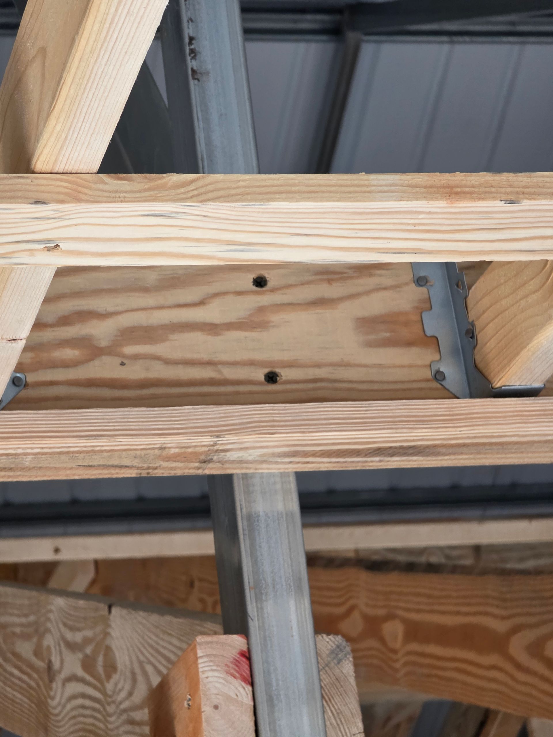Wooden roof supports with metal brackets and a metal roof.