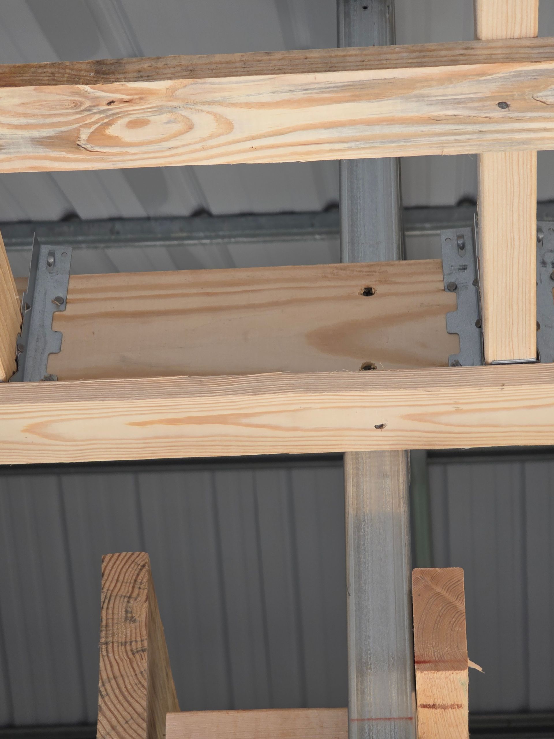 Wooden beams and plywood bracing support a metal roof structure.