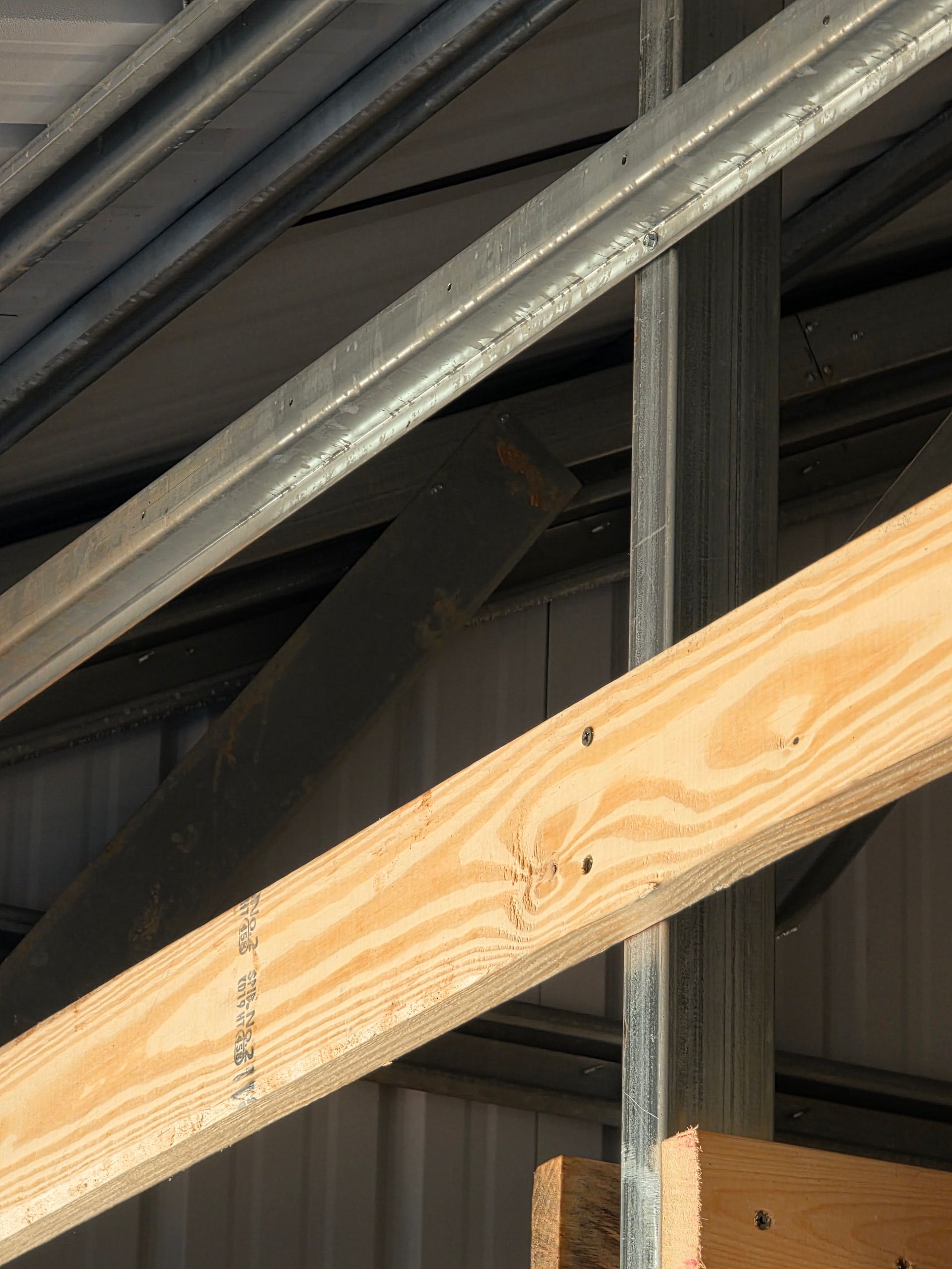 Metal and wooden structural beams in a building, with a vertical metal support.
