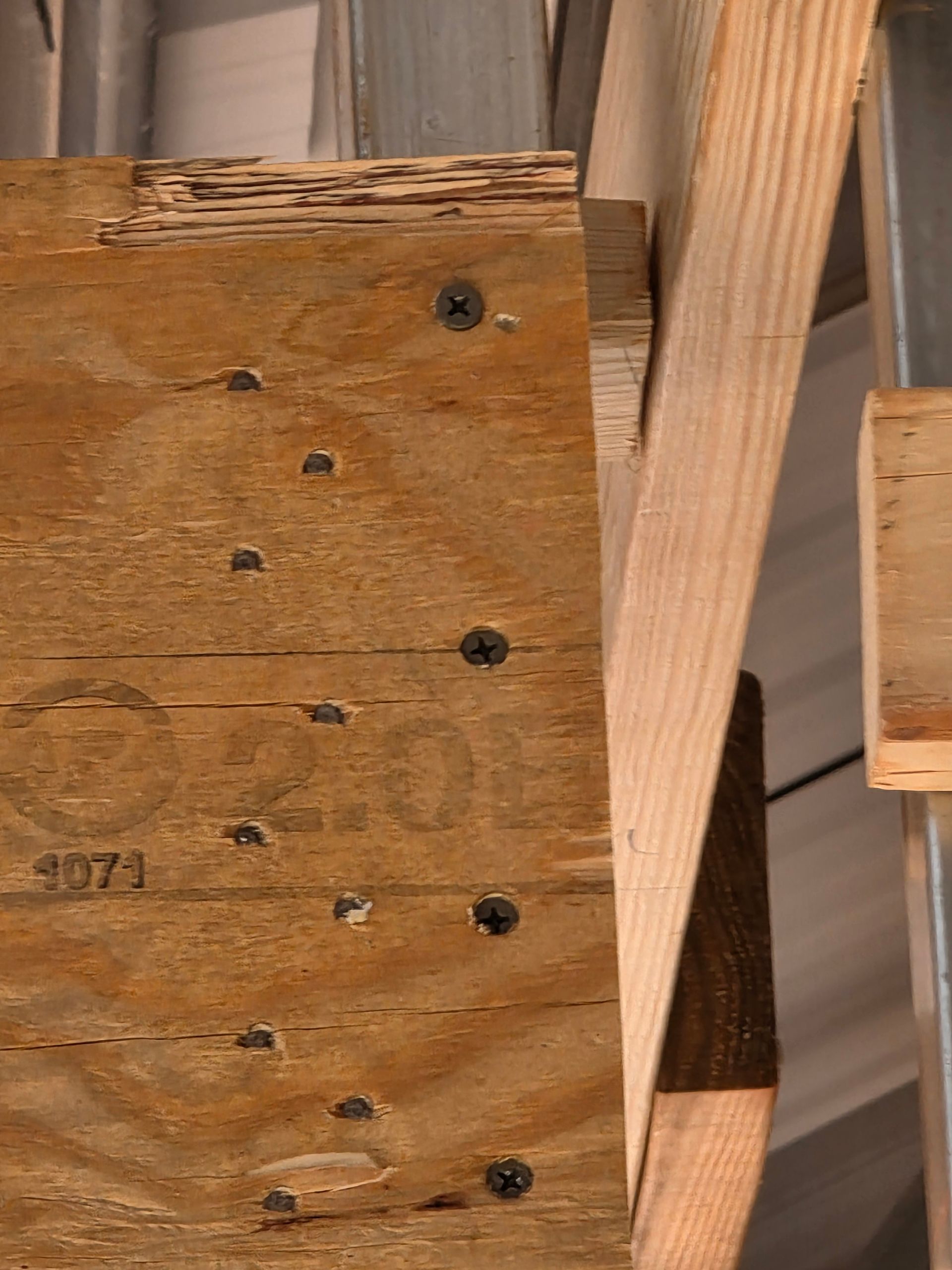 Close-up of wooden structure, with screws.  A damaged piece of wood is attached to a support.
