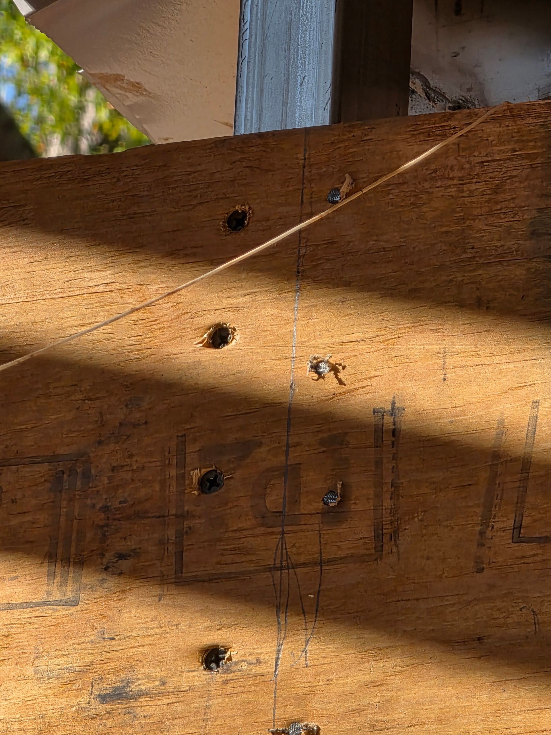 Wooden surface with drawn markings, several holes, and a thin string.