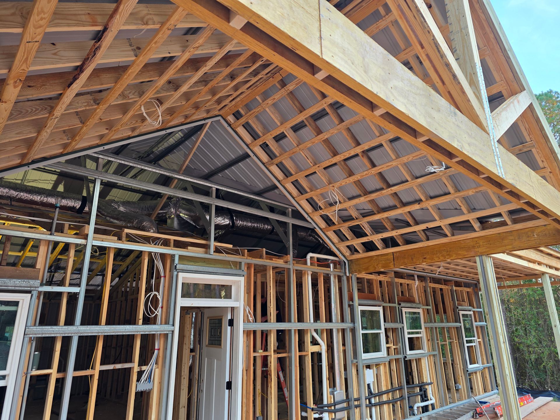 Building under construction; wooden framing, roof trusses, and metal studs visible.
