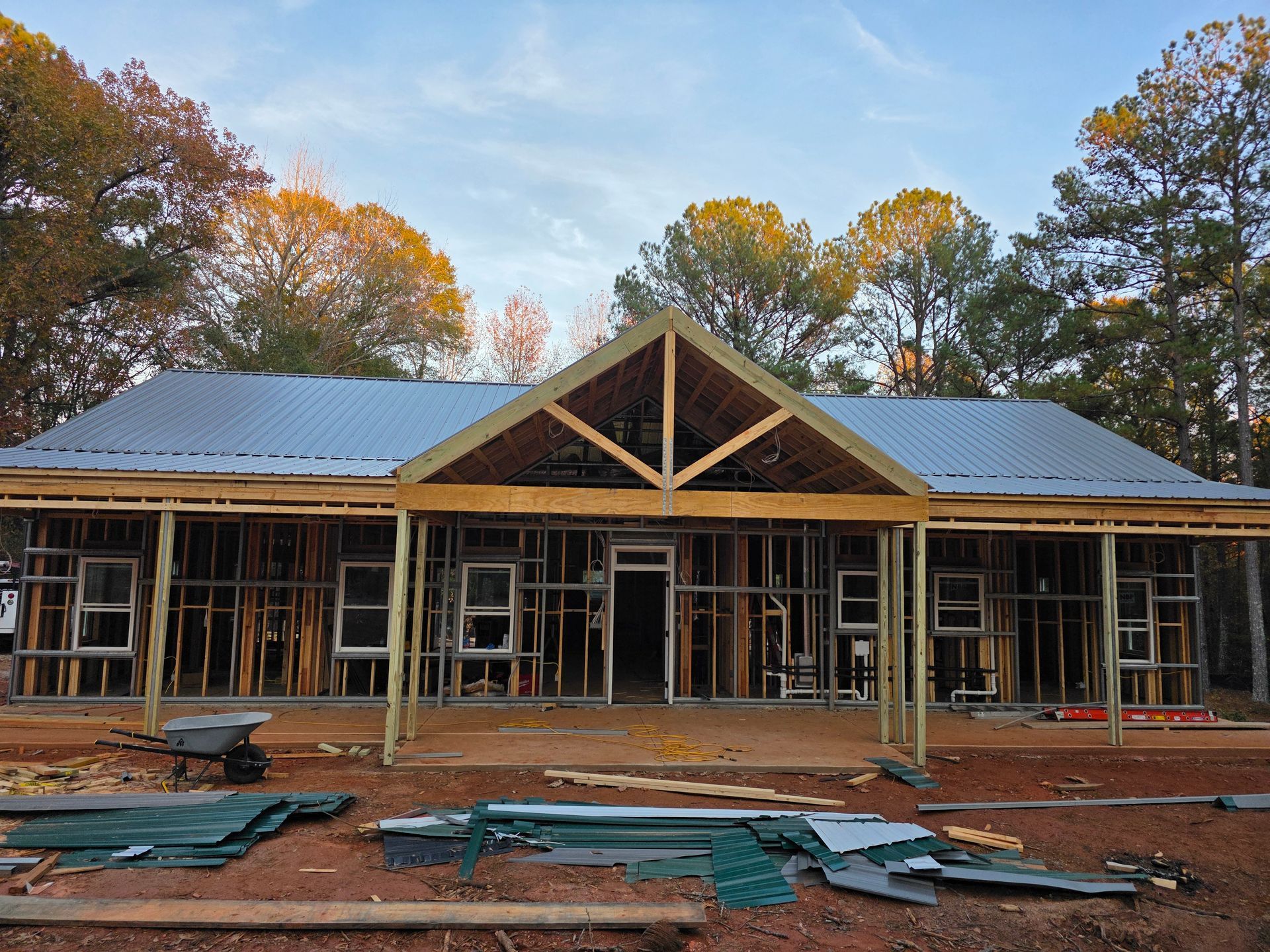 House under construction with exposed wooden frame and metal roof.