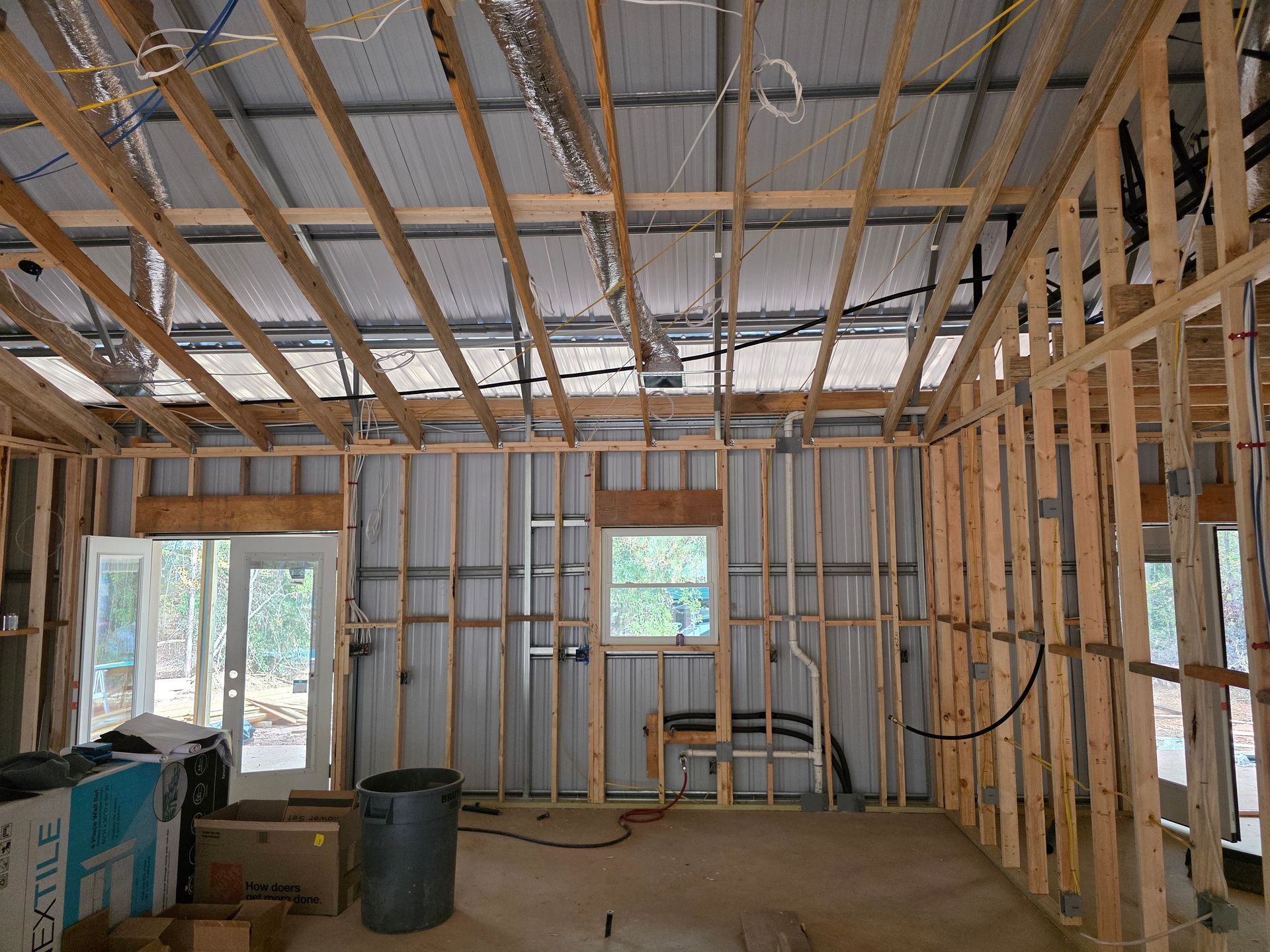 Interior of a building under construction, wooden frames, metal walls, exposed wiring and plumbing.