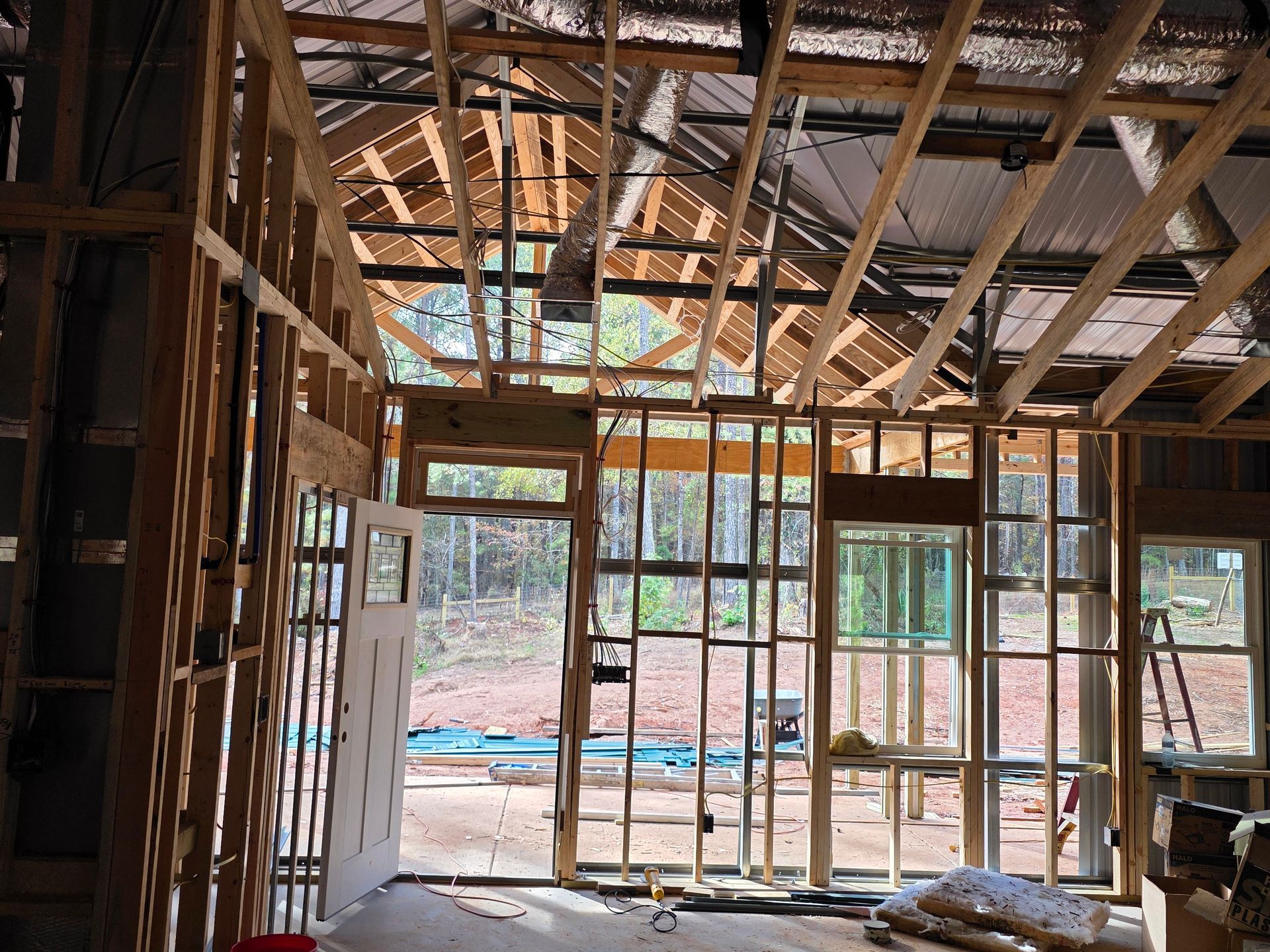 Interior view of a building under construction, framed with wood. Exposed roof, windows, and a doorway.