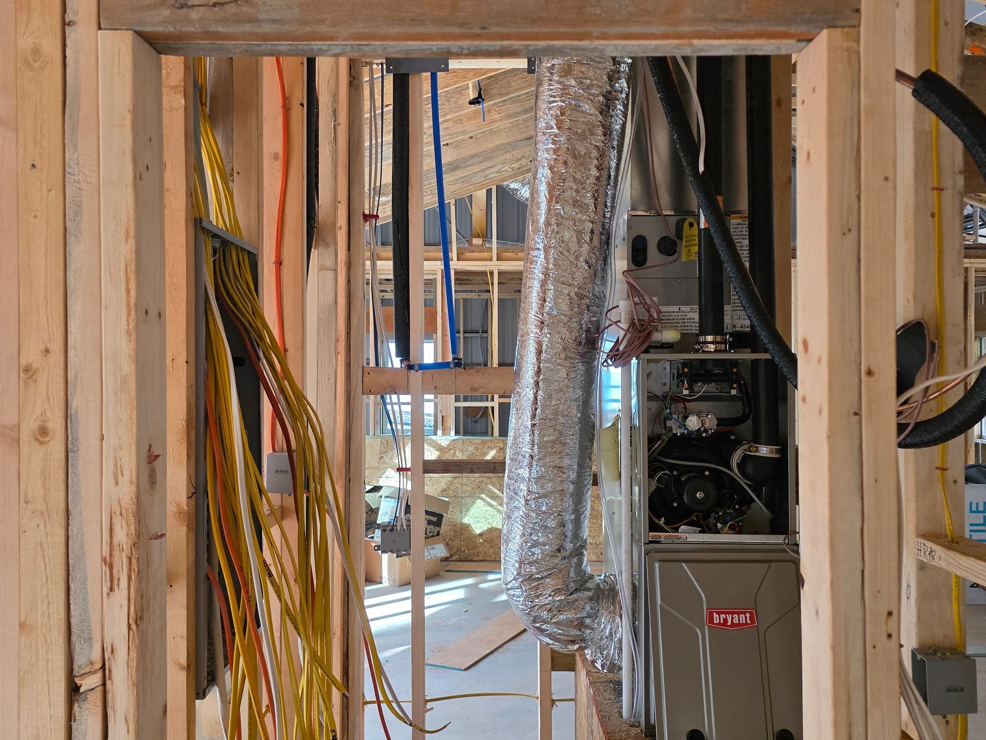 Interior view of a building under construction, showing framing, wiring, HVAC system, and ductwork.