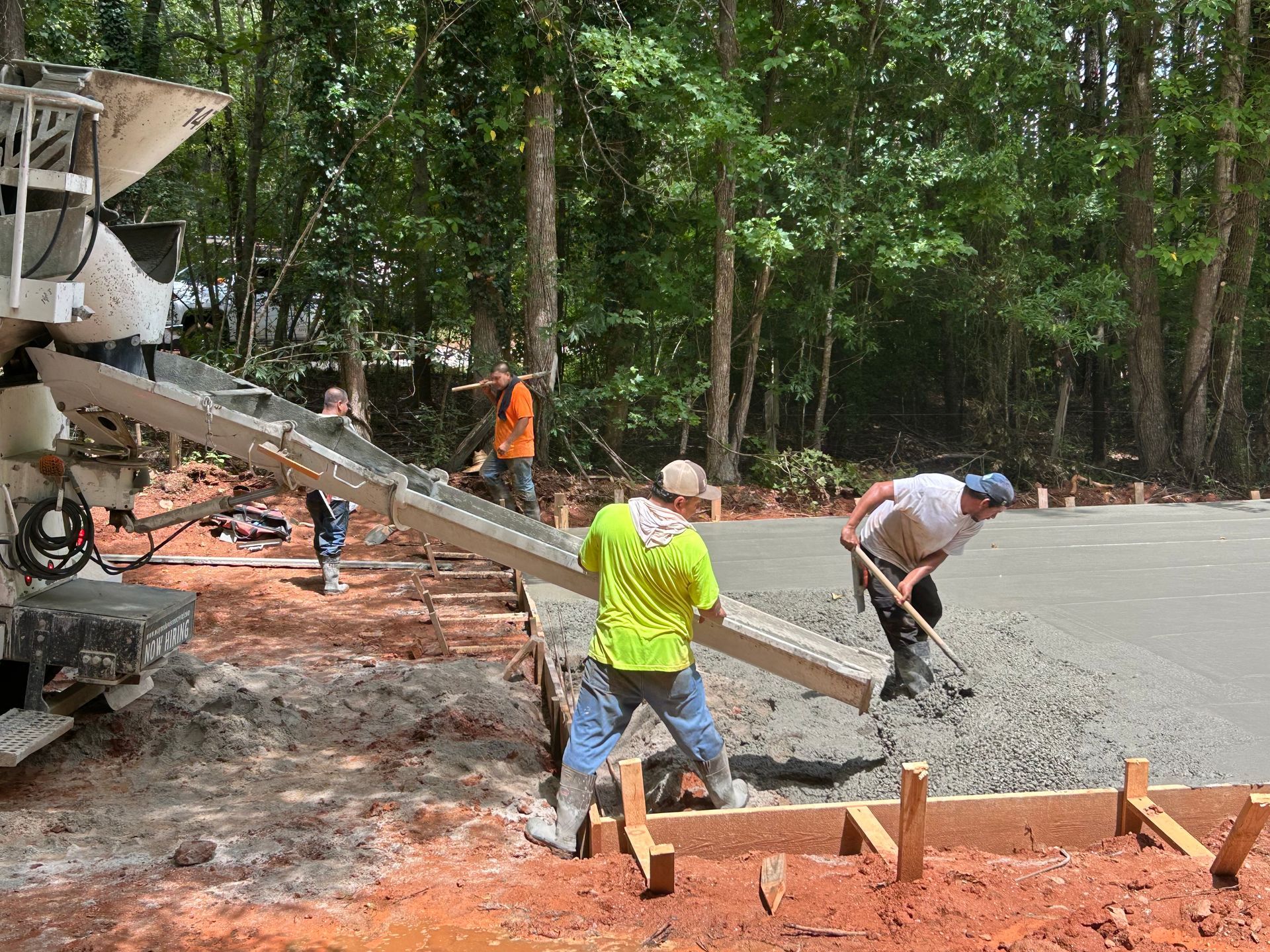 Construction workers pouring concrete from a truck to form a foundation, outdoors.