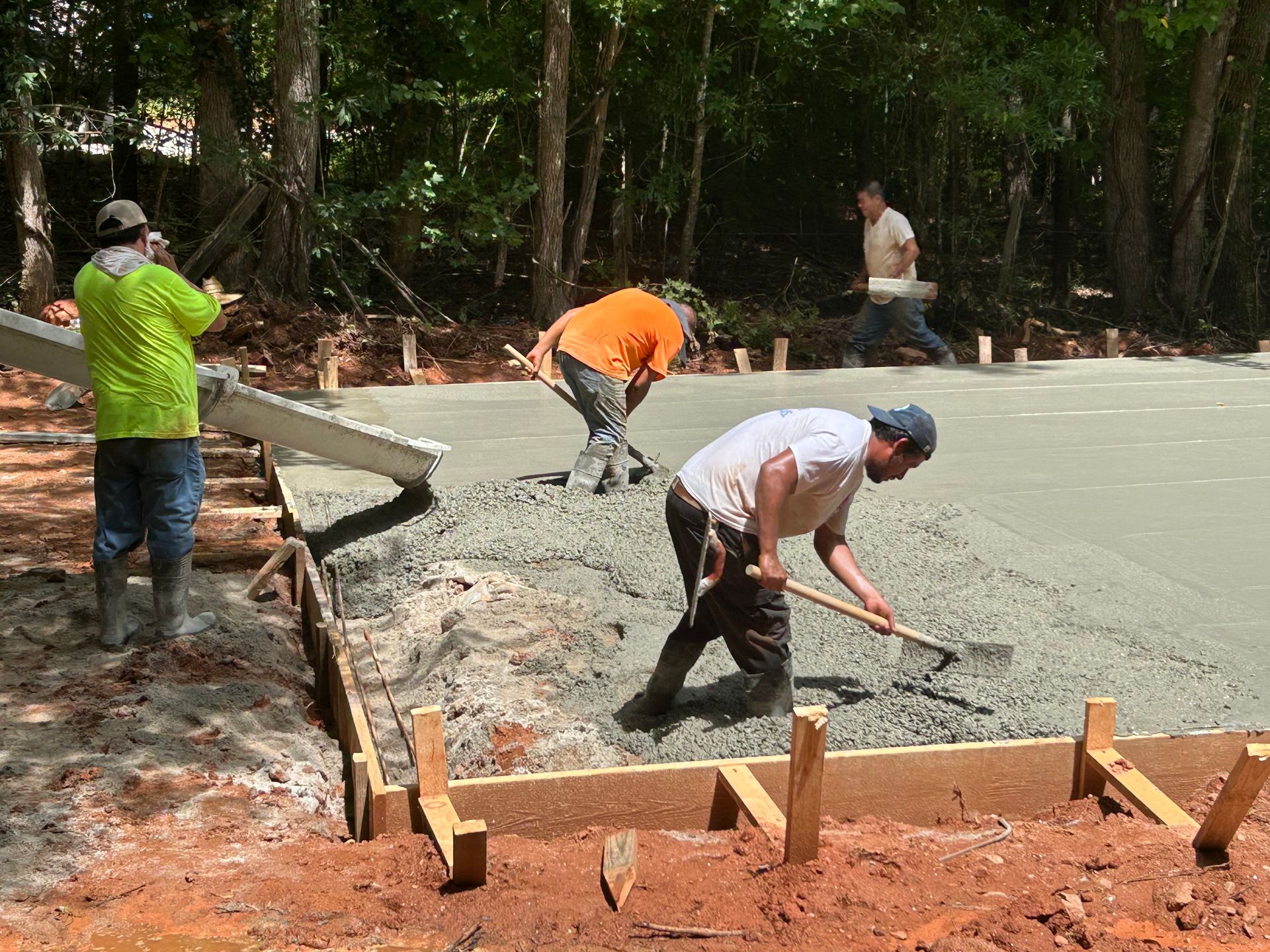 Construction workers pouring and leveling concrete for a slab outdoors.